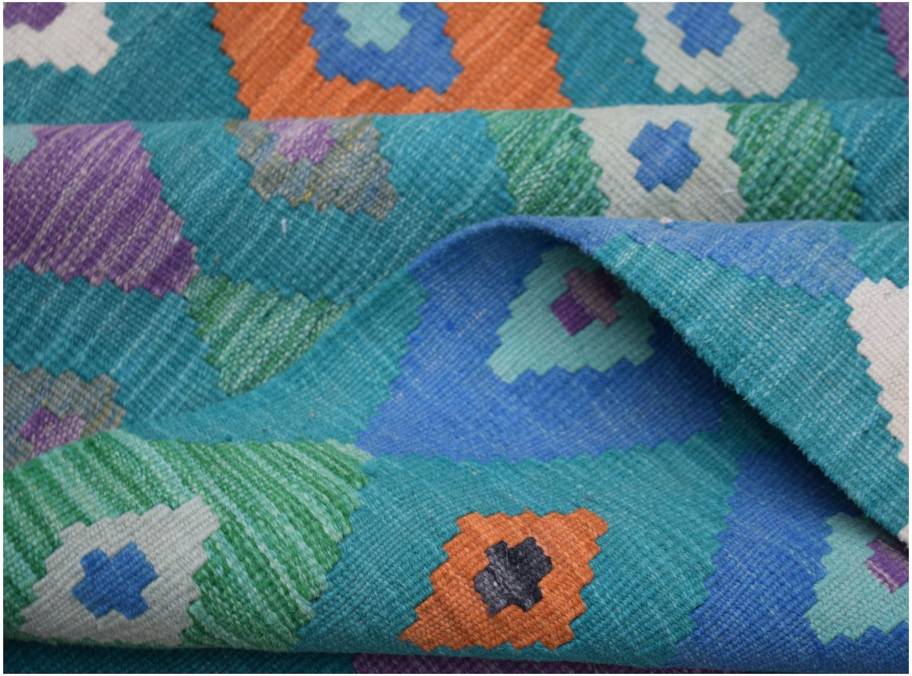A handmade Afghan Maimana kilim rug featuring a vibrant geometric pattern in wool.