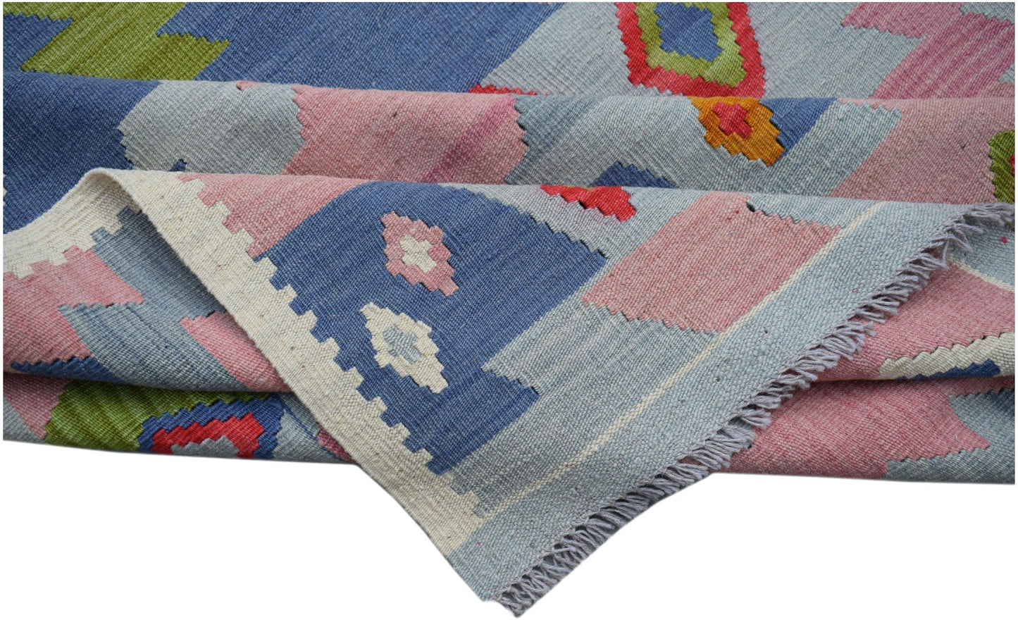 A handwoven Afghan Maimana kilim rug featuring geometric patterns in blue, pink, and green wool.
