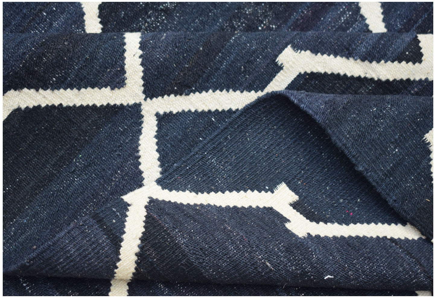 A handmade Afghan Maimana kilim rug featuring a dark blue field with a white geometric pattern.