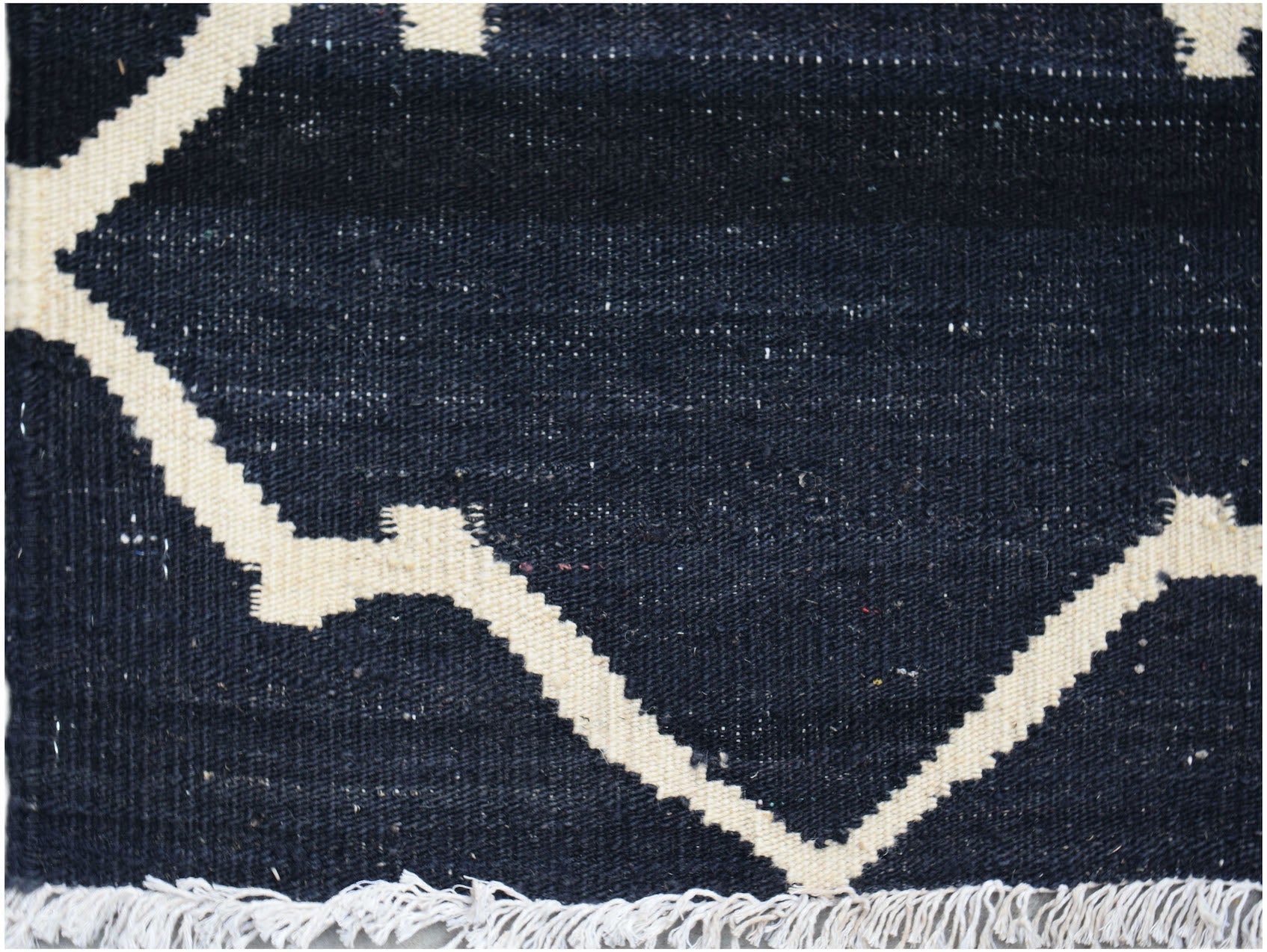 Handwoven Afghan Maimana kilim rug featuring a geometric cream pattern on a dark blue background.