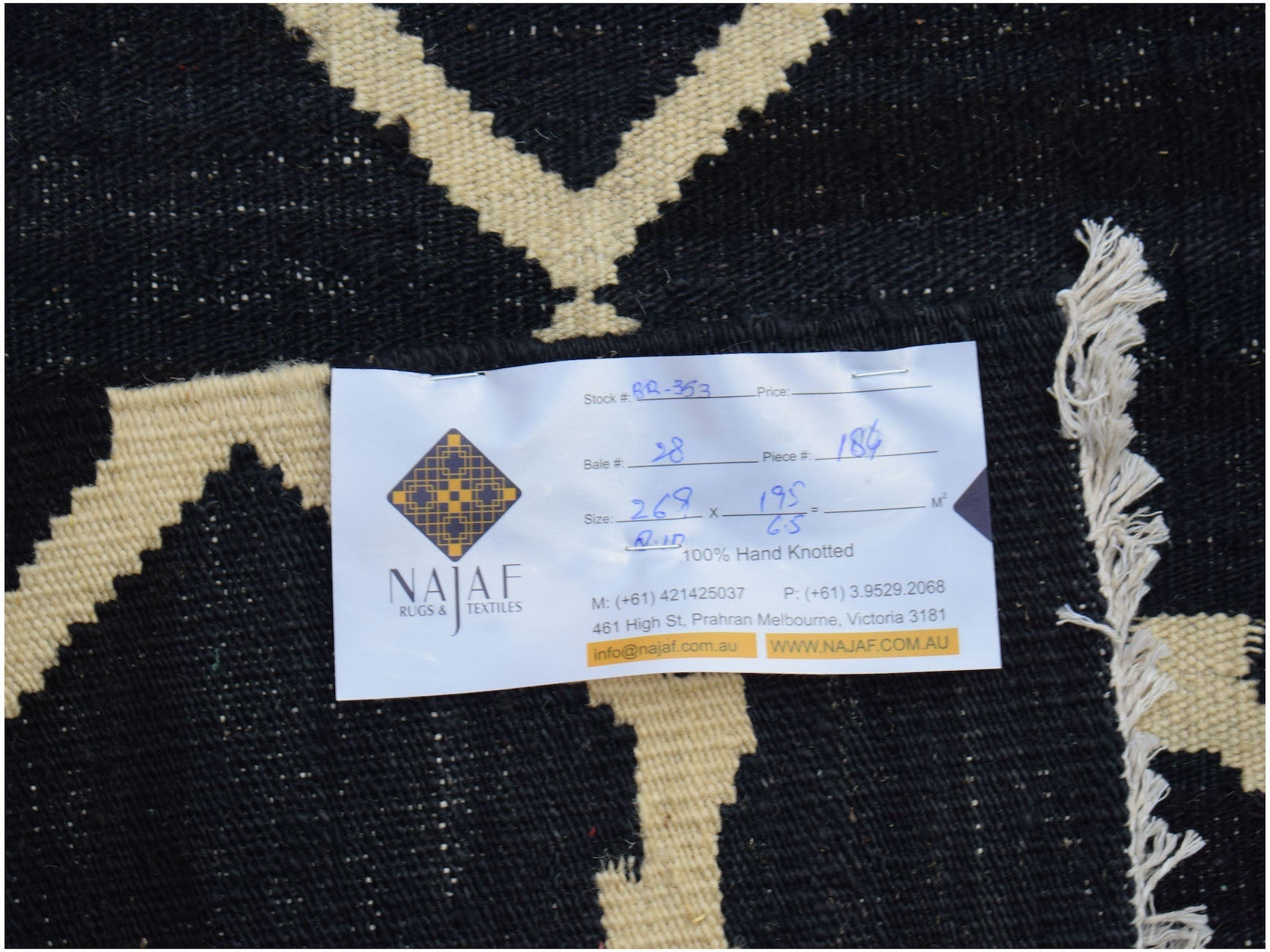 An Afghan Maimana kilim rug featuring a geometric pattern in black and cream wool.