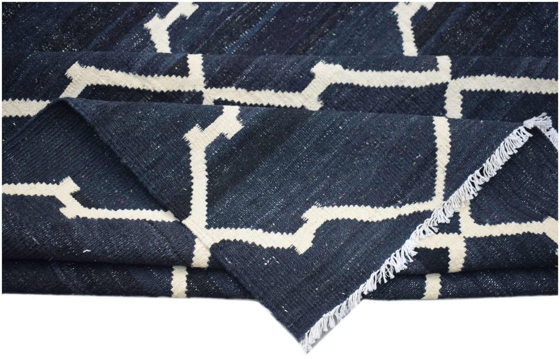 A handmade Afghan Maimana kilim rug featuring a dark blue and white geometric pattern.