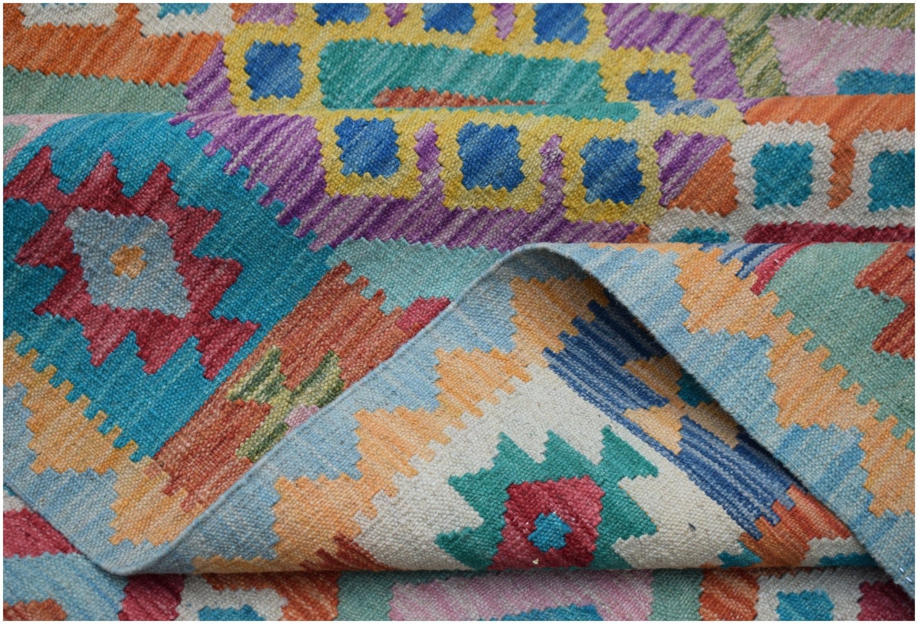A handwoven Afghan Maimana kilim rug featuring a vibrant geometric pattern in wool.