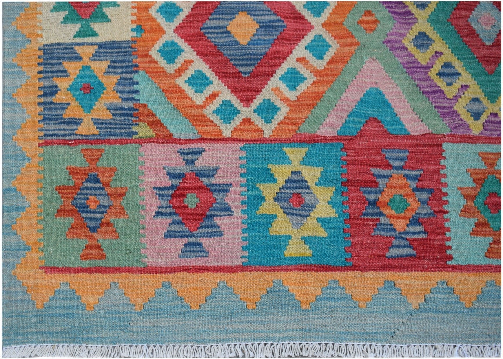 Handwoven Afghan Maimana kilim rug featuring a vibrant geometric pattern in multicolored wool.