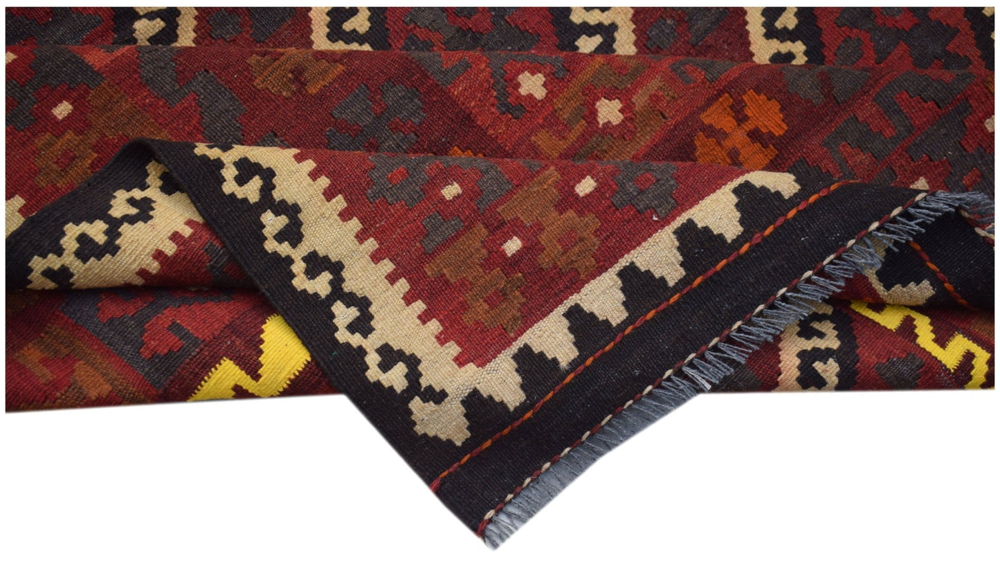 A handwoven Afghan Maimana kilim rug featuring geometric patterns in red, black, and cream wool.