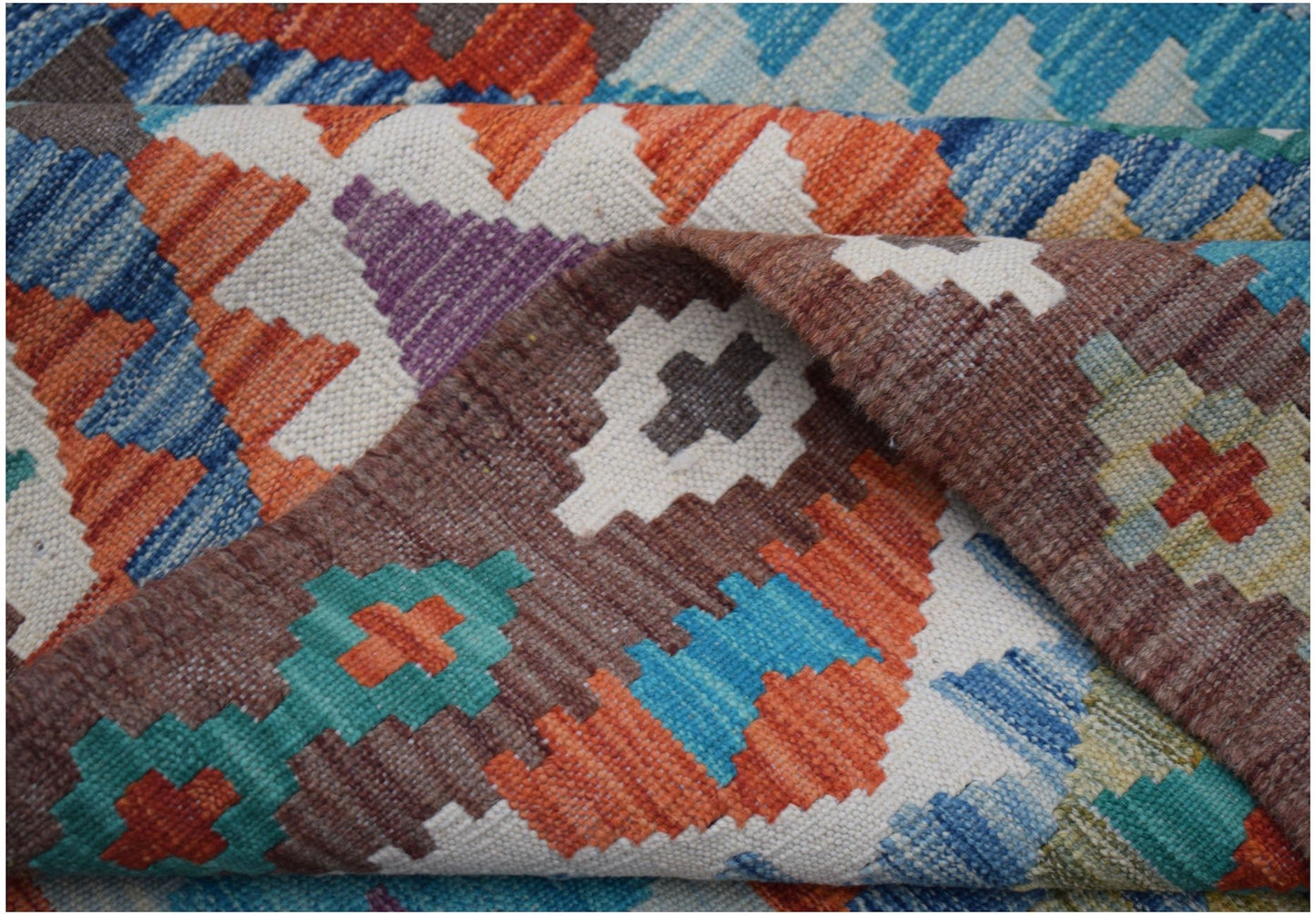 A handwoven Afghan Maimana kilim rug featuring a vibrant geometric pattern in wool.