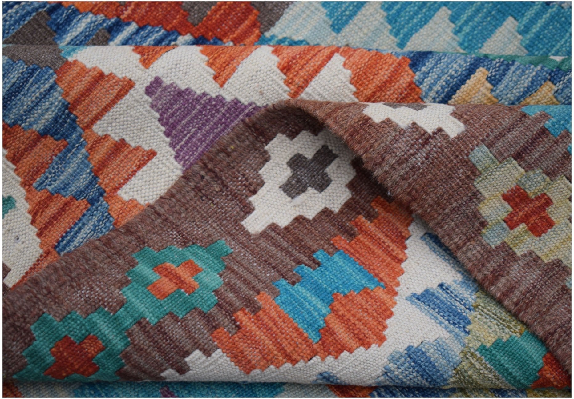 A handwoven Afghan Maimana kilim rug featuring a vibrant geometric pattern in wool.