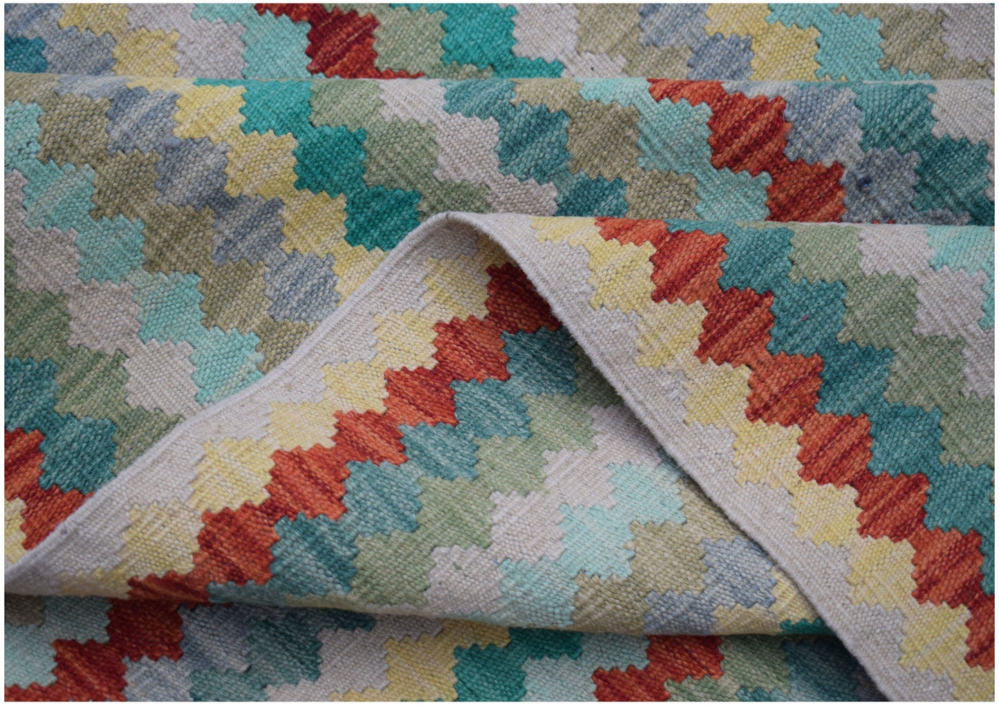 A handmade Afghan Maimana kilim rug featuring a colorful geometric pattern in wool.