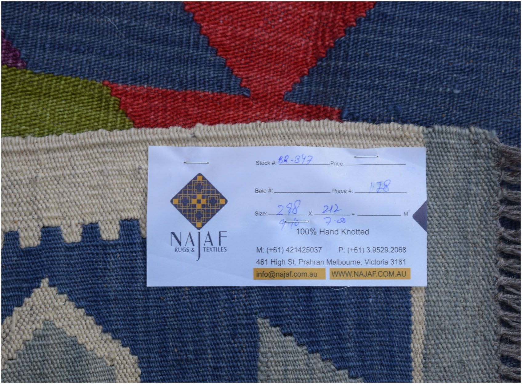 A handwoven Afghan Maimana kilim rug featuring a geometric pattern in blue, red, and green tones.