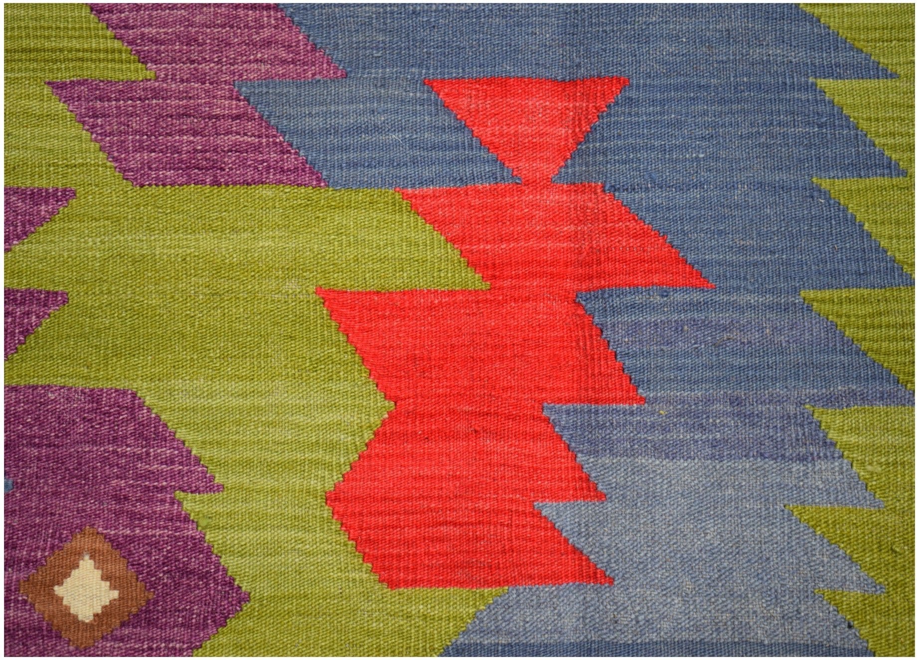 A handwoven Afghan Maimana kilim rug featuring a geometric pattern in red, blue, green, and purple.