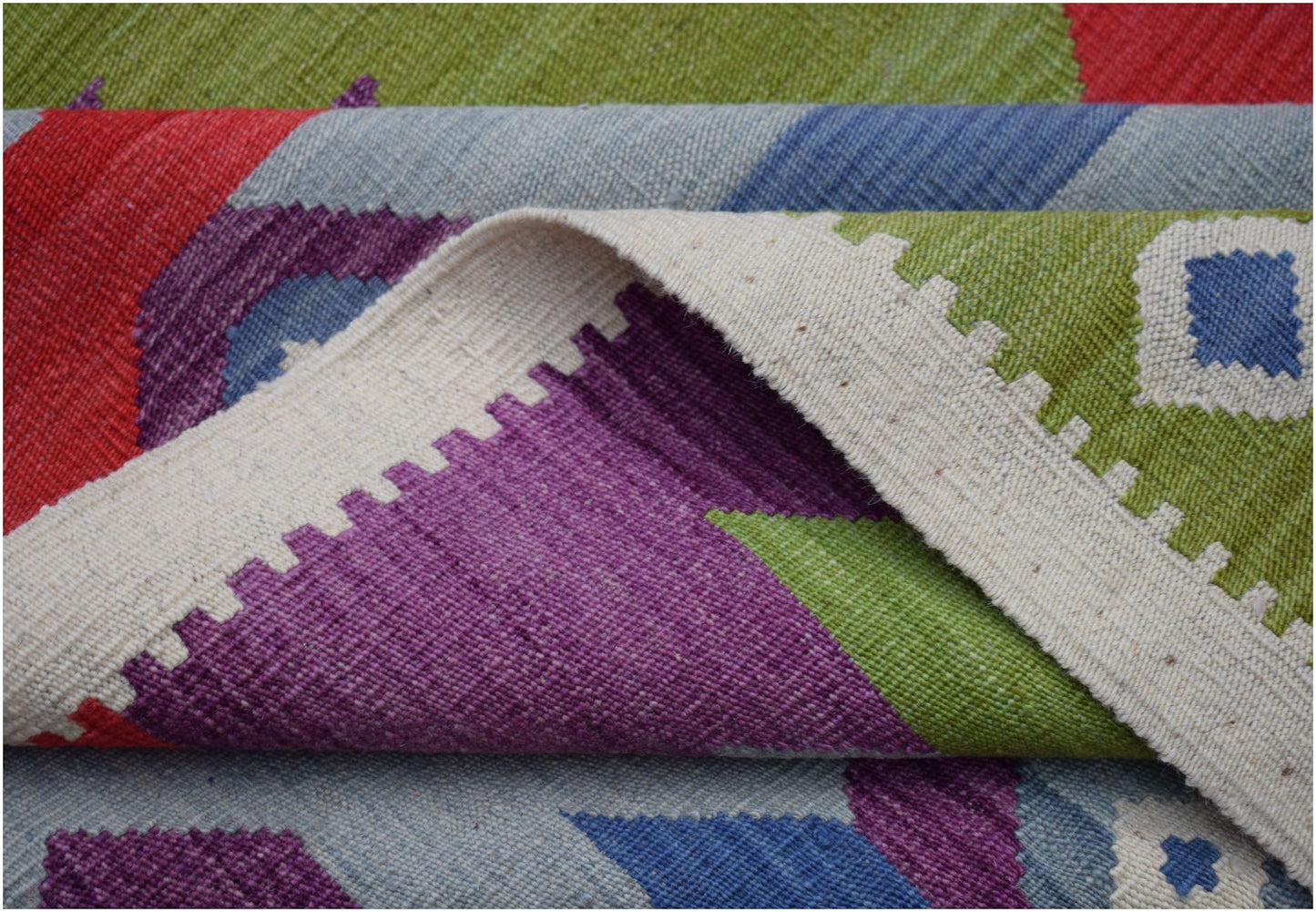 A handwoven Afghan Maimana kilim rug featuring a vibrant geometric pattern in wool.