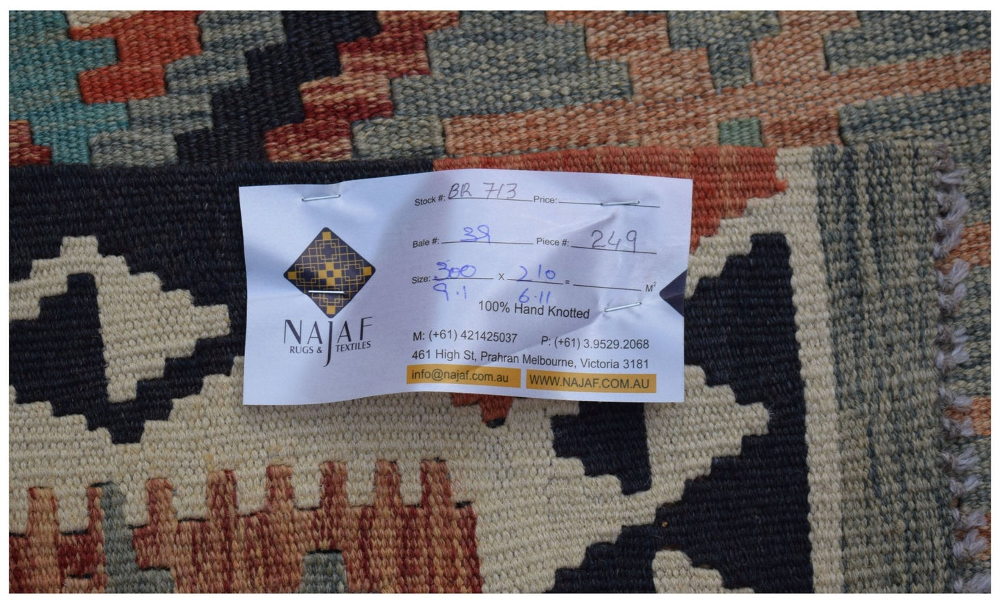 A handwoven Afghan Maimana kilim rug featuring a geometric pattern in earthy tones.