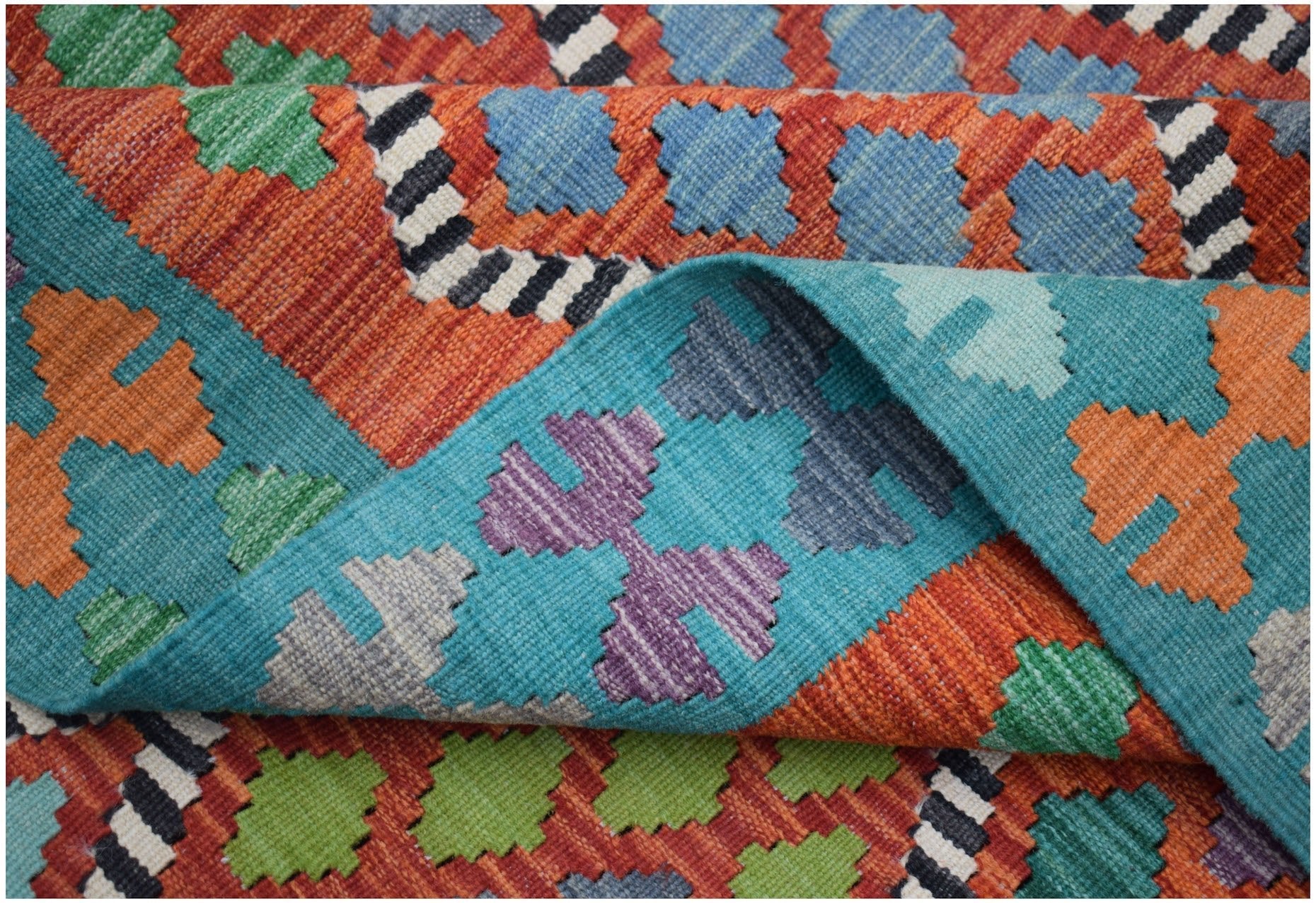 A handmade Afghan Maimana kilim rug featuring a vibrant geometric pattern in wool.