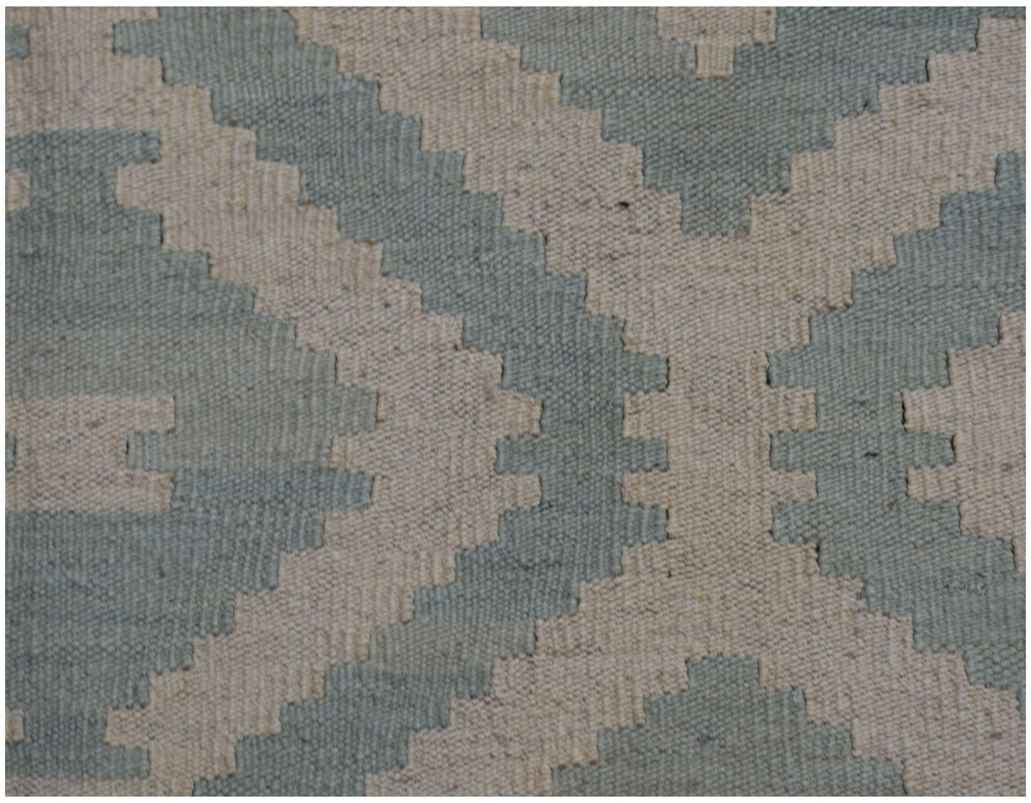 A handmade Afghan Maimana kilim rug featuring a geometric pattern in sage green and cream wool.