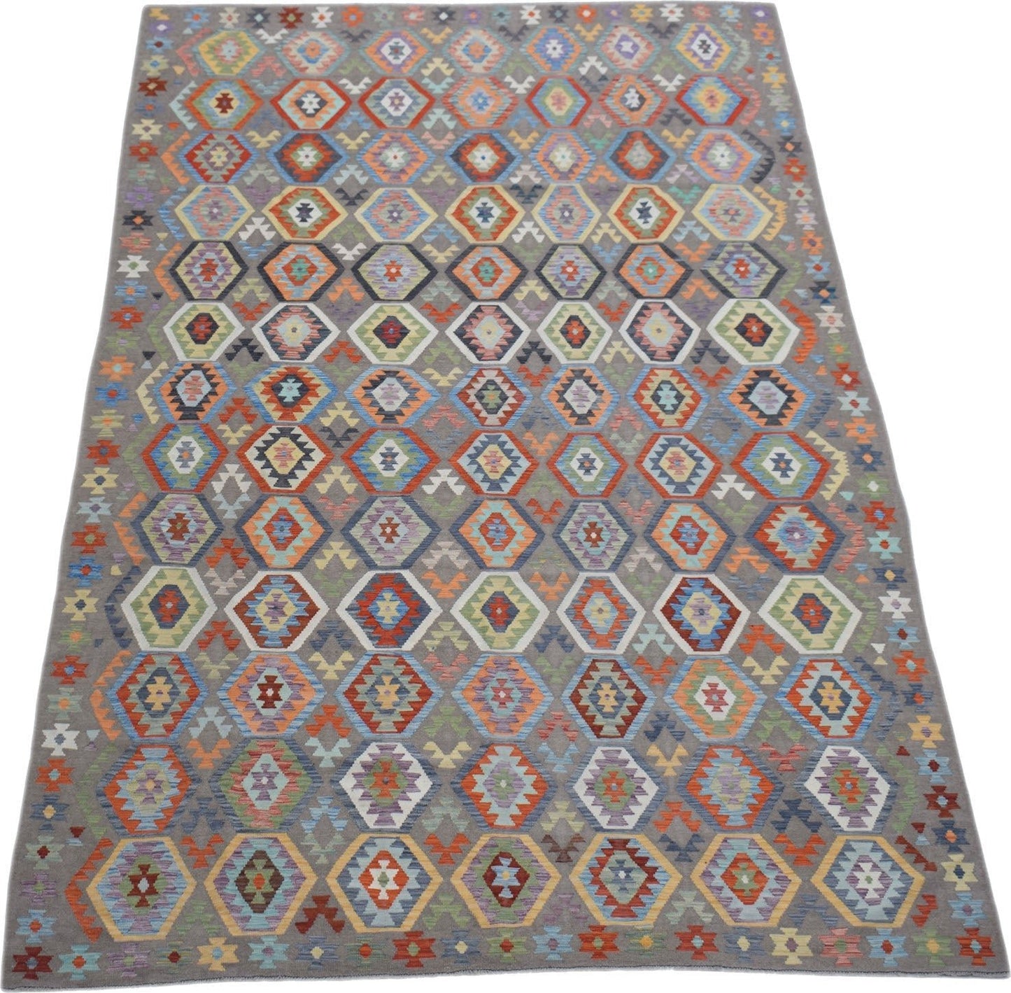 Handwoven Afghan Maimana kilim rug featuring a colorful geometric pattern on a grey background.