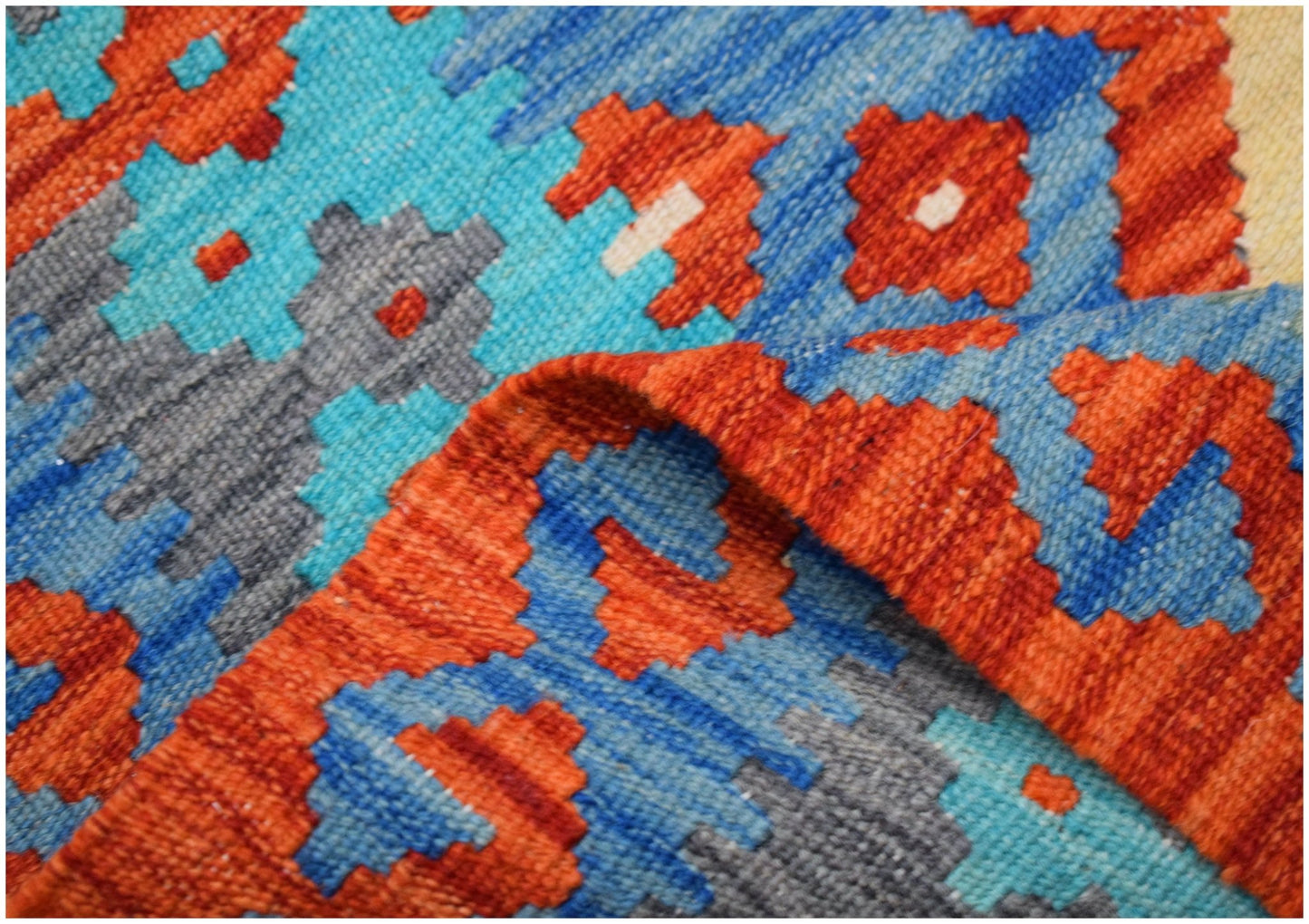A close-up of a handmade Afghan Maimana kilim runner featuring geometric patterns in wool.