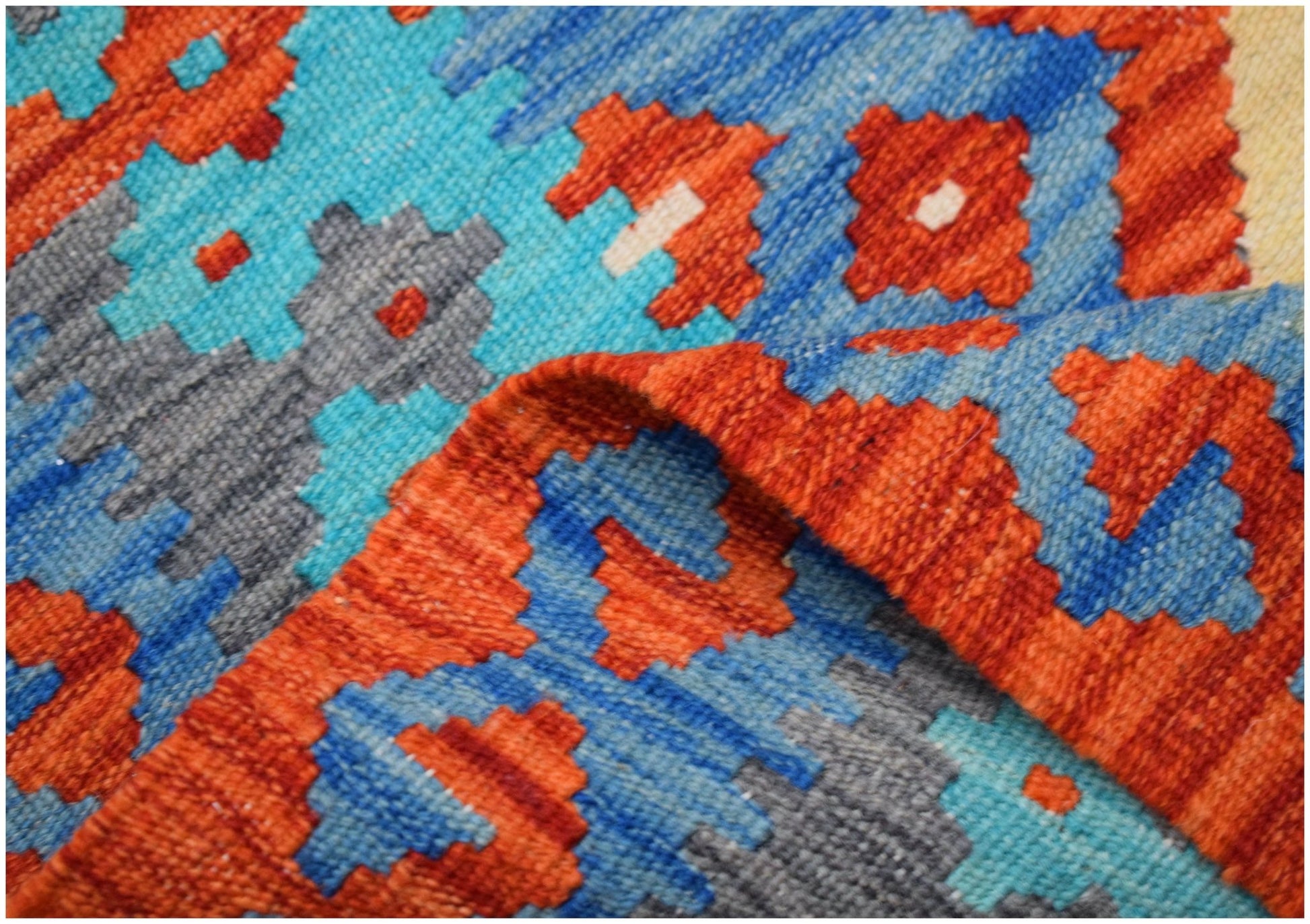 A close-up of a handmade Afghan Maimana kilim runner featuring geometric patterns in wool.