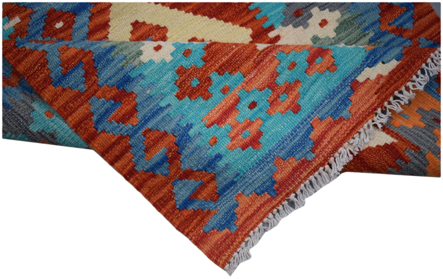 A handmade Afghan Maimana wool runner featuring a vibrant geometric pattern in blue and orange.