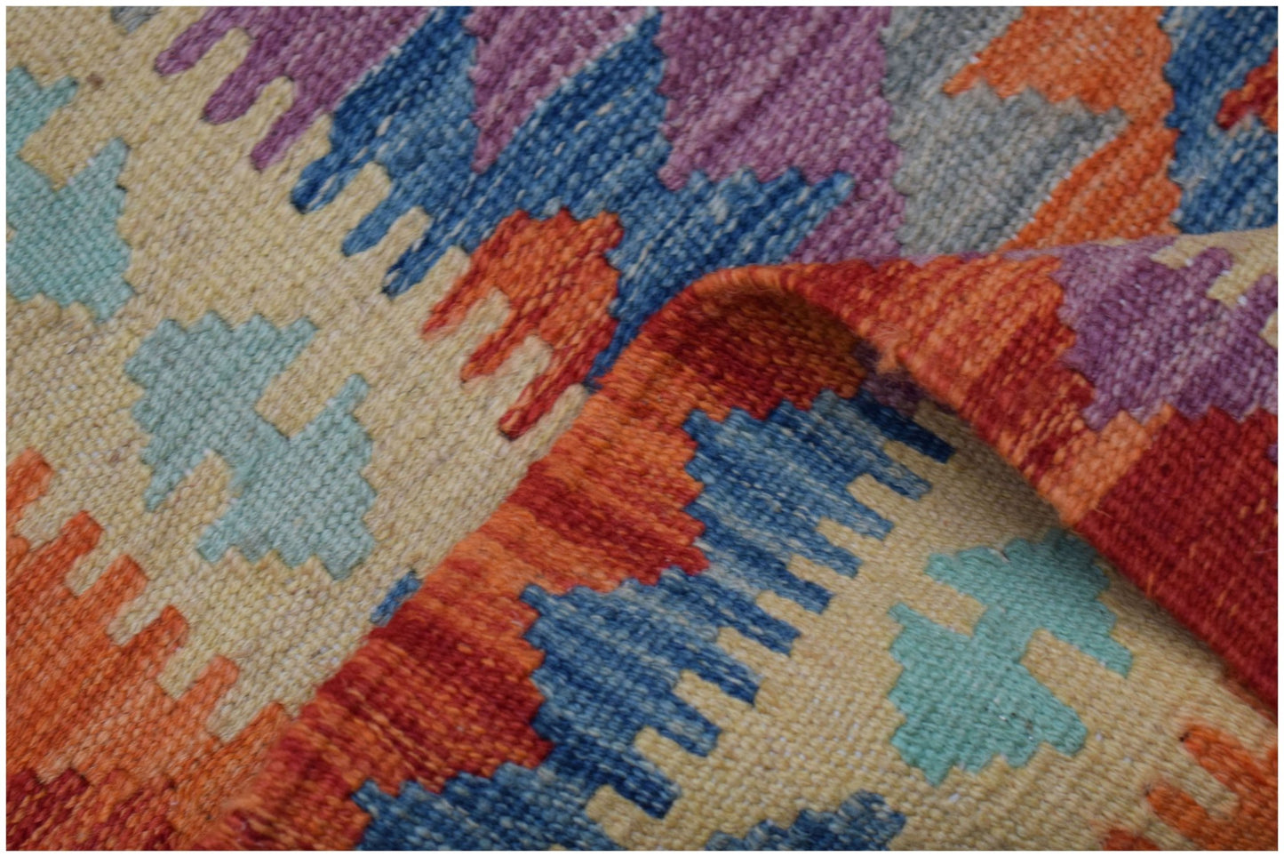 A handmade Afghan Maimana kilim runner featuring a geometric pattern in vibrant wool colors.