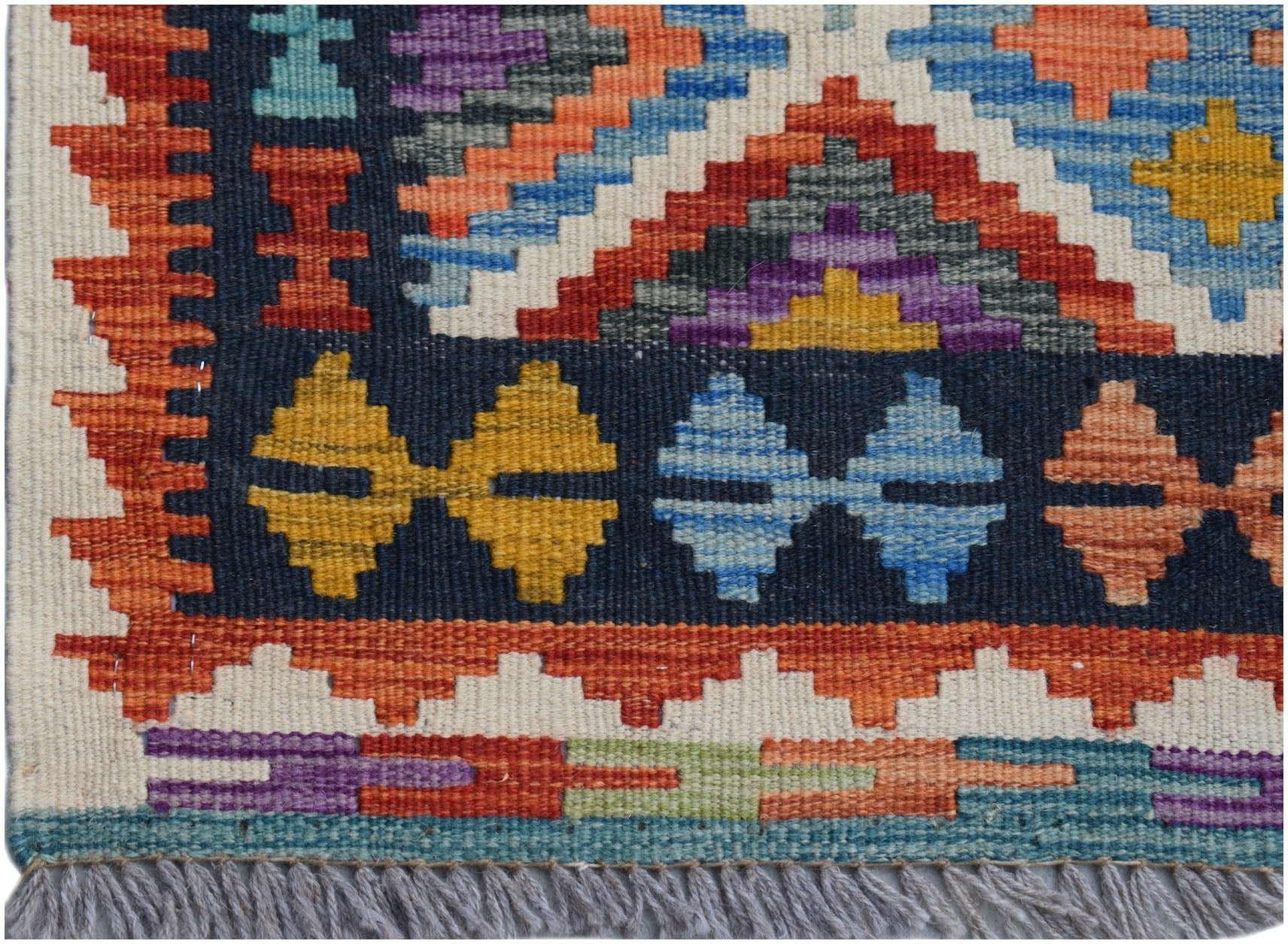 A handmade Afghan Maimana kilim runner featuring a geometric pattern in vibrant wool colors.