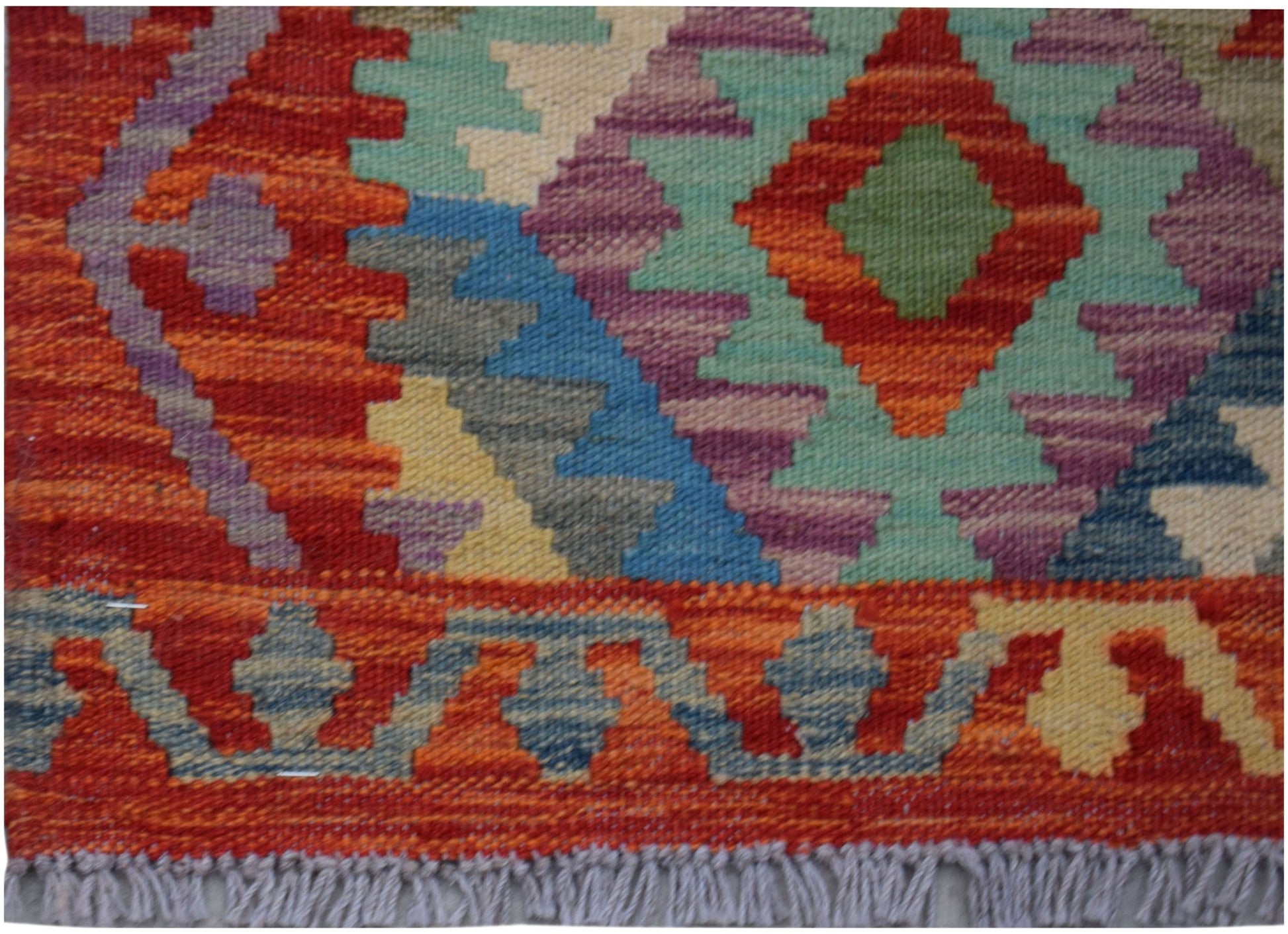 Handwoven Afghan Maimana wool runner featuring a colorful geometric pattern and fringed edges.