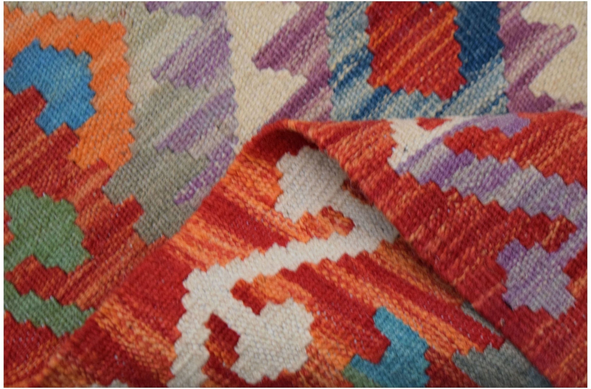 A handwoven Afghan Maimana kilim runner featuring a geometric pattern in vibrant wool colors.