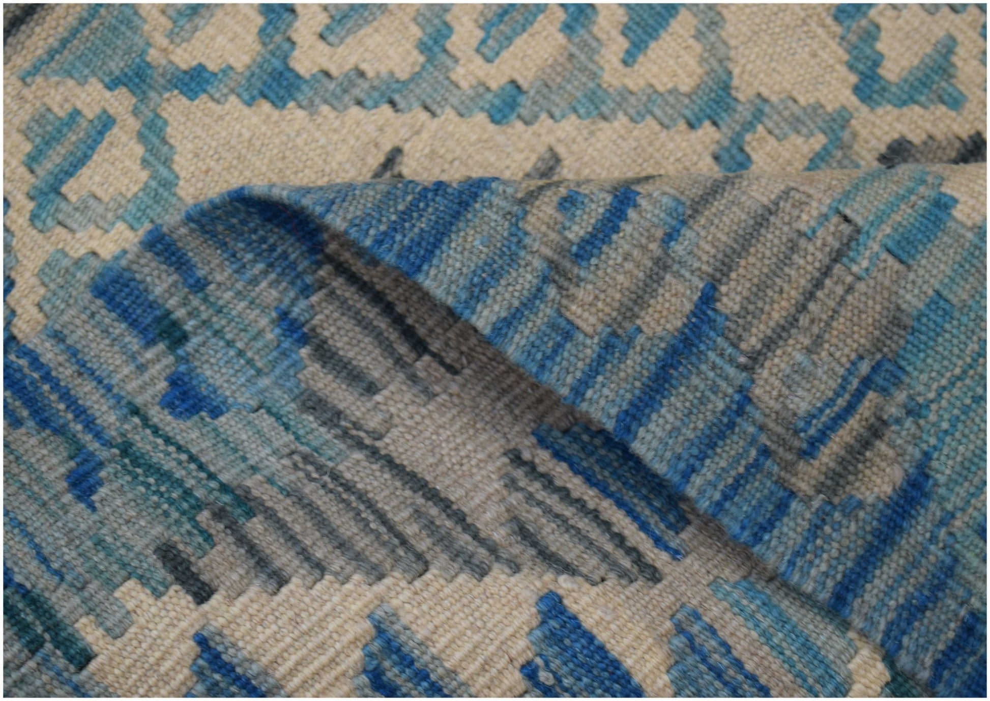 A handwoven Afghan Maimana wool kilim runner featuring a geometric pattern in blue and cream tones.