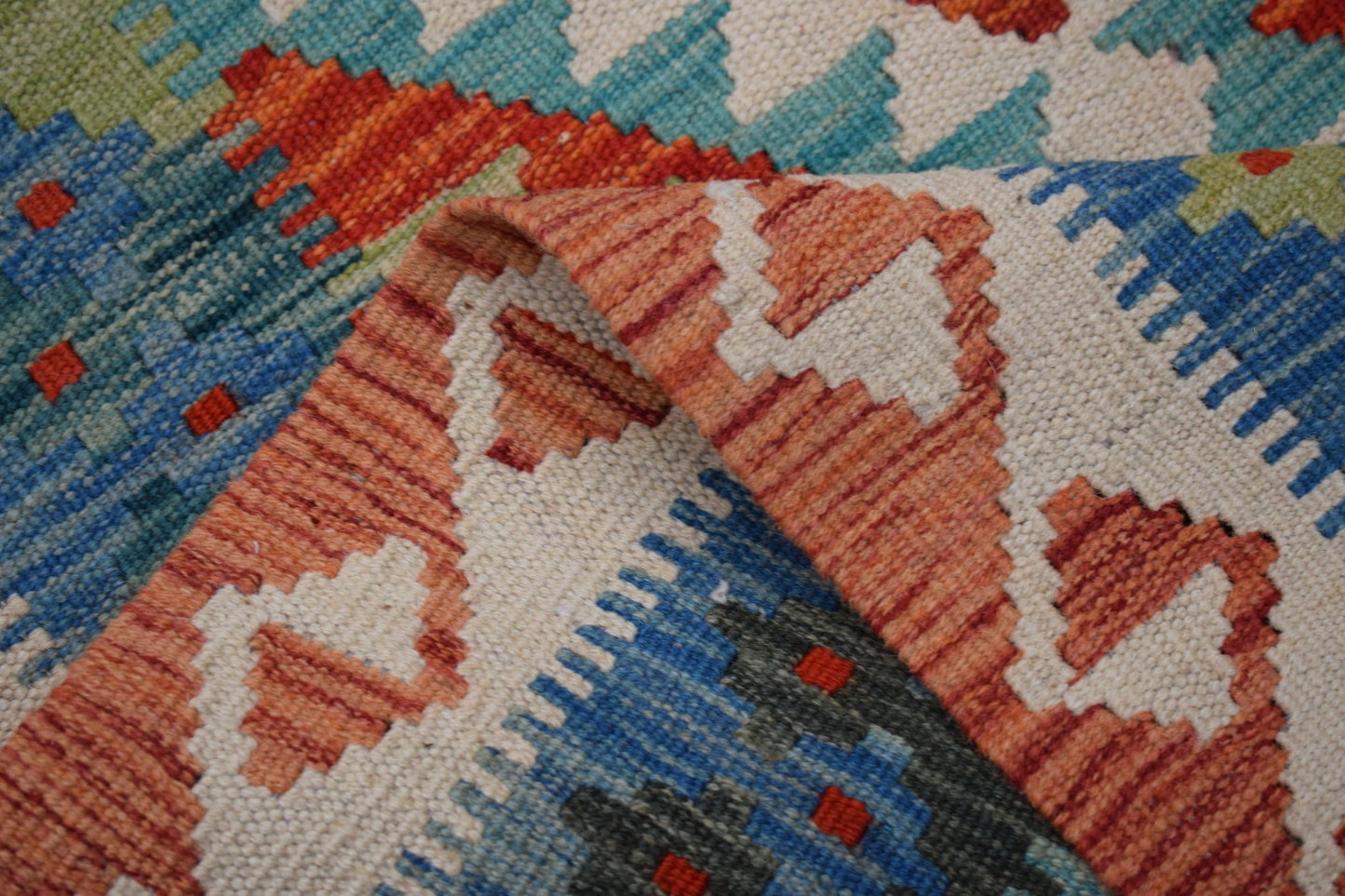 A handmade Afghan Maimana kilim runner featuring a geometric pattern in orange, blue, and cream.