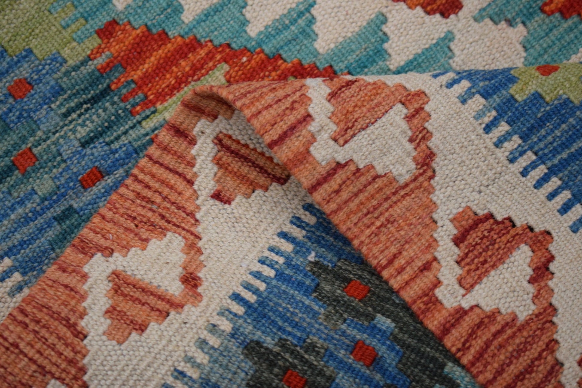 A handmade Afghan Maimana kilim runner featuring a geometric pattern in orange, blue, and cream.