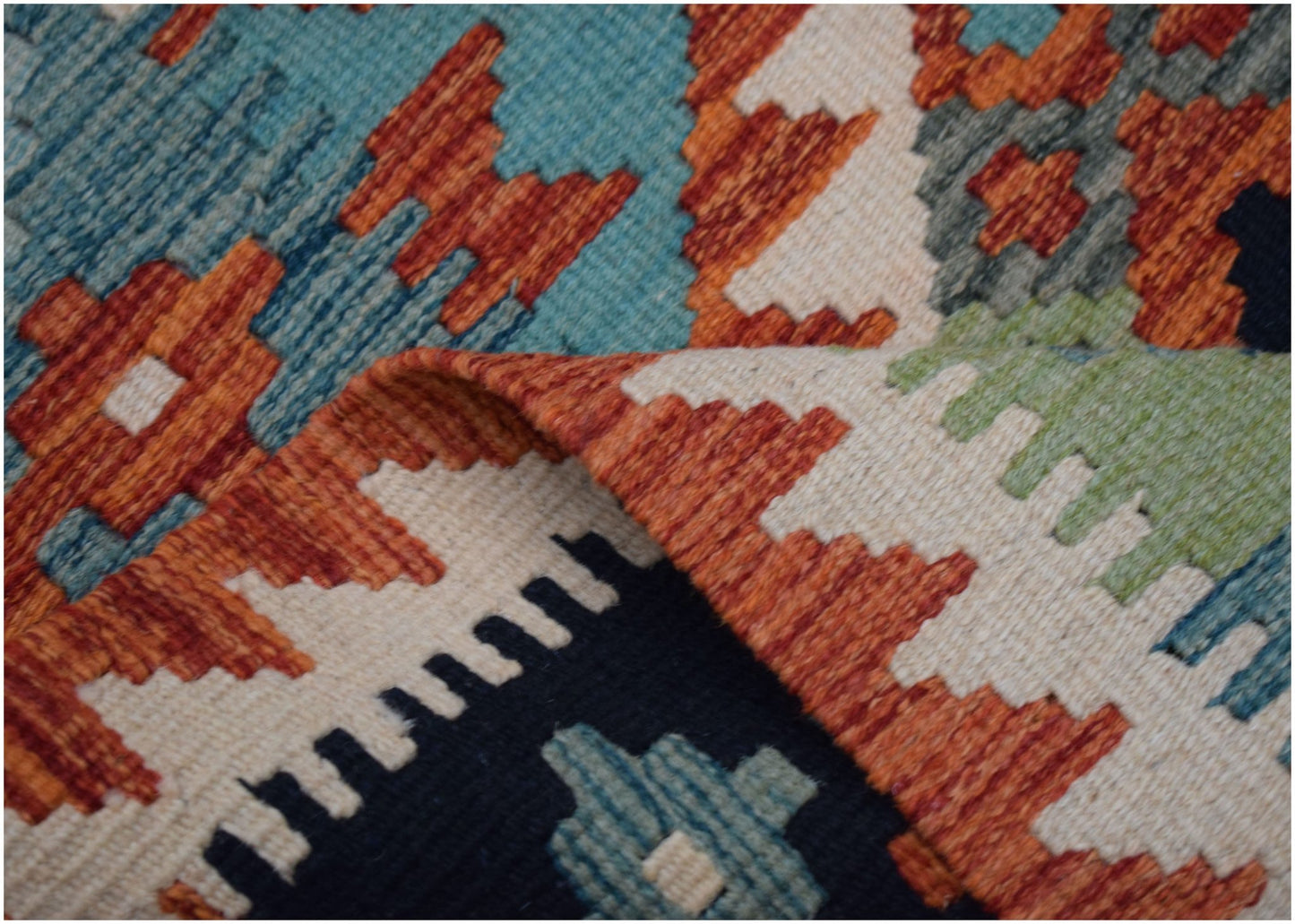 A close-up of a handwoven Afghan Maimana kilim runner featuring geometric patterns in wool.