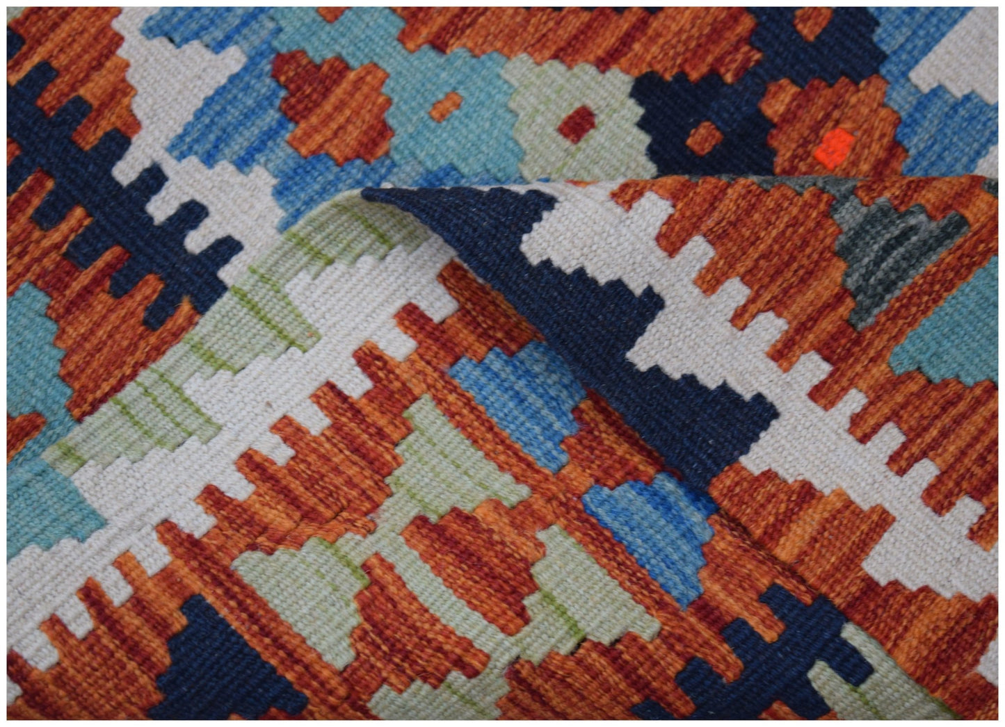 A handwoven wool kilim runner featuring a geometric pattern in orange, blue, and cream tones.