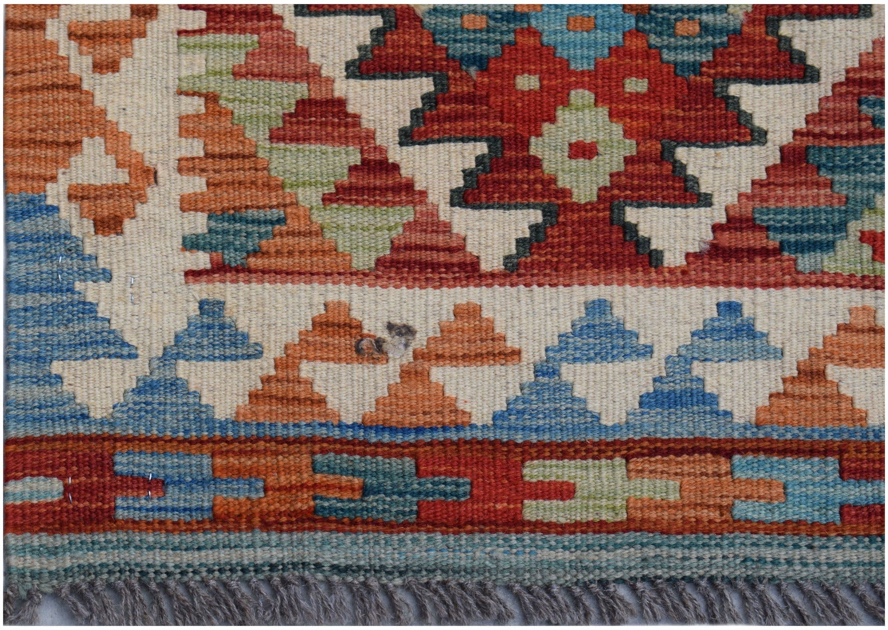 Handwoven Afghan Maimana kilim runner featuring geometric patterns in red, blue, and orange wool.
