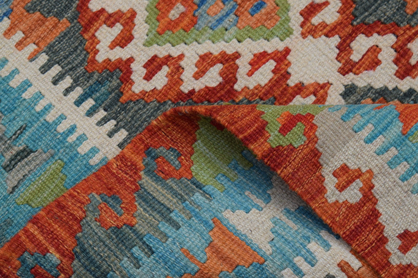 A handmade Afghan Maimana wool kilim runner featuring a geometric pattern in orange, blue, and green.