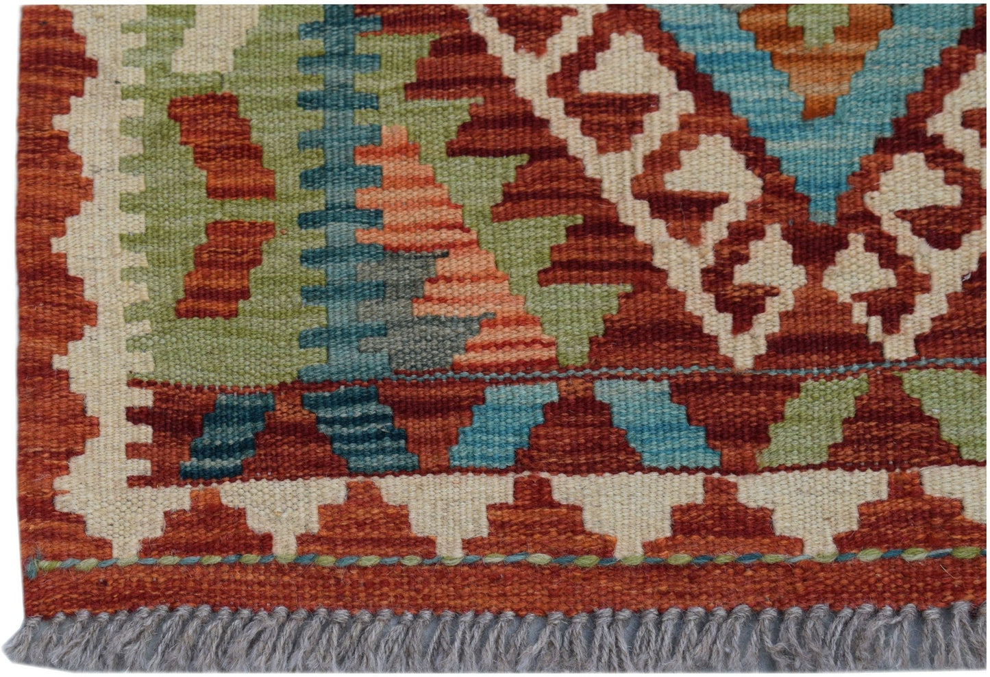 A close-up of an Afghan Maimana Kilim runner featuring geometric patterns in red, green, and blue.