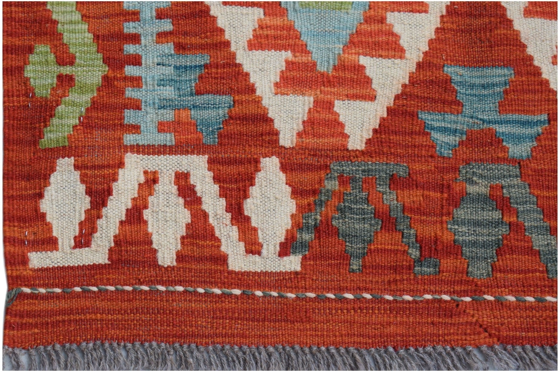 Handwoven Afghan Maimana kilim runner featuring geometric patterns in red, blue, and green wool.