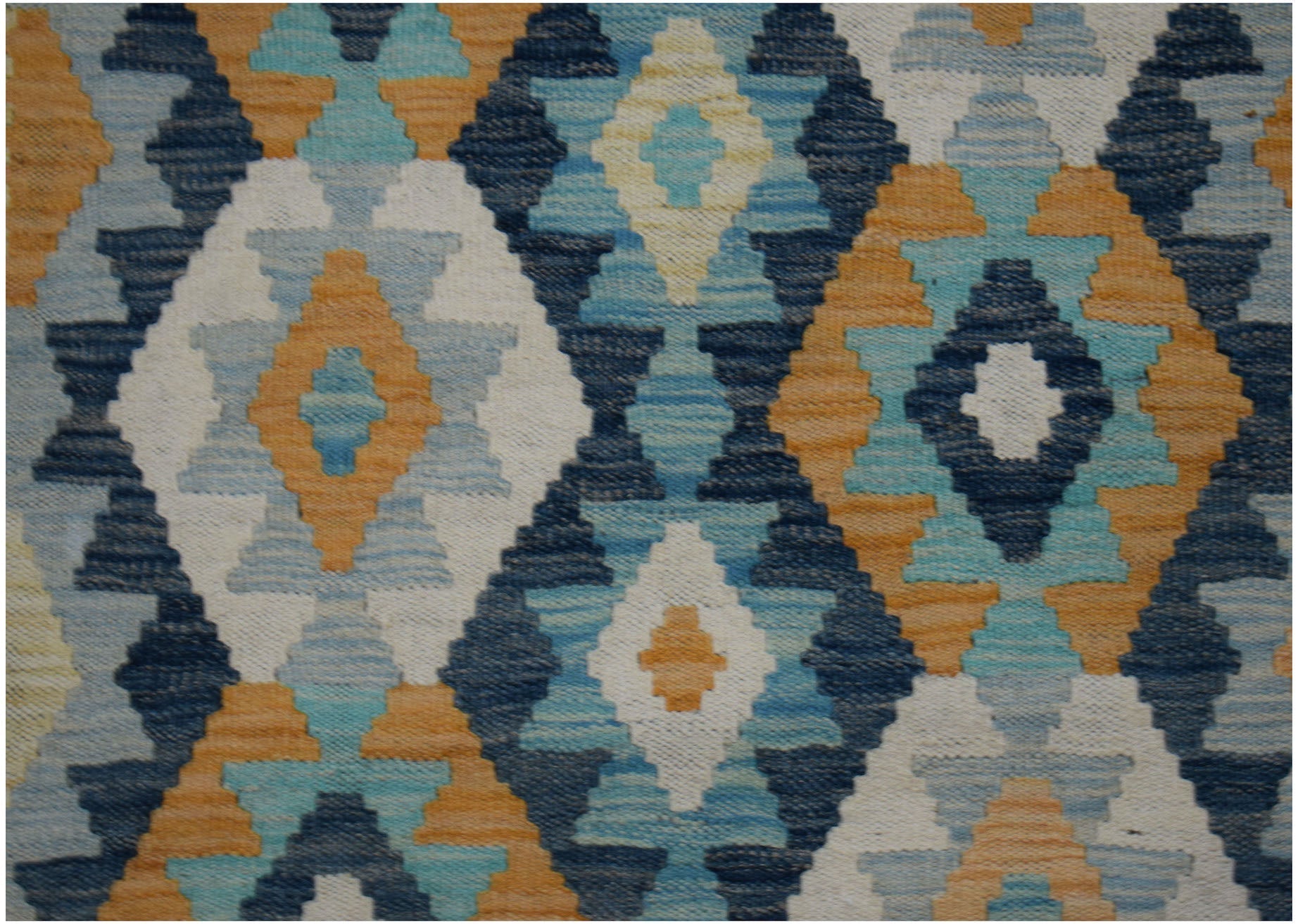 Handwoven wool runner featuring a geometric diamond pattern in shades of blue, orange, and cream.