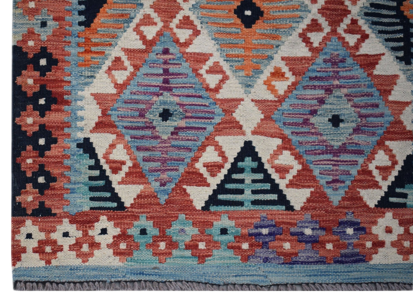 Handwoven Afghan Maimana kilim runner featuring a geometric pattern in red, blue, and purple.