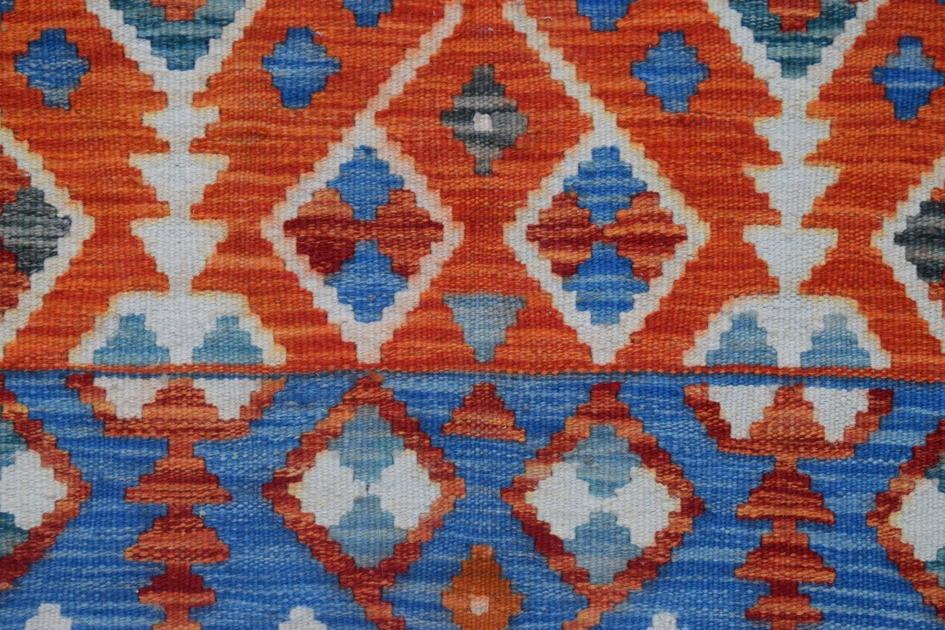 Handwoven Afghan Maimana kilim runner featuring a geometric pattern in orange and blue wool.