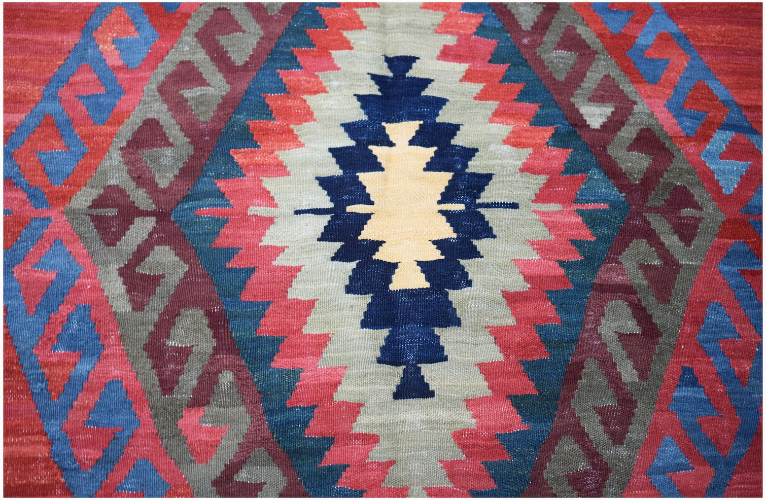 Handwoven Afghan Mazari Sharif kilim featuring a geometric diamond pattern in red, blue, and tan.