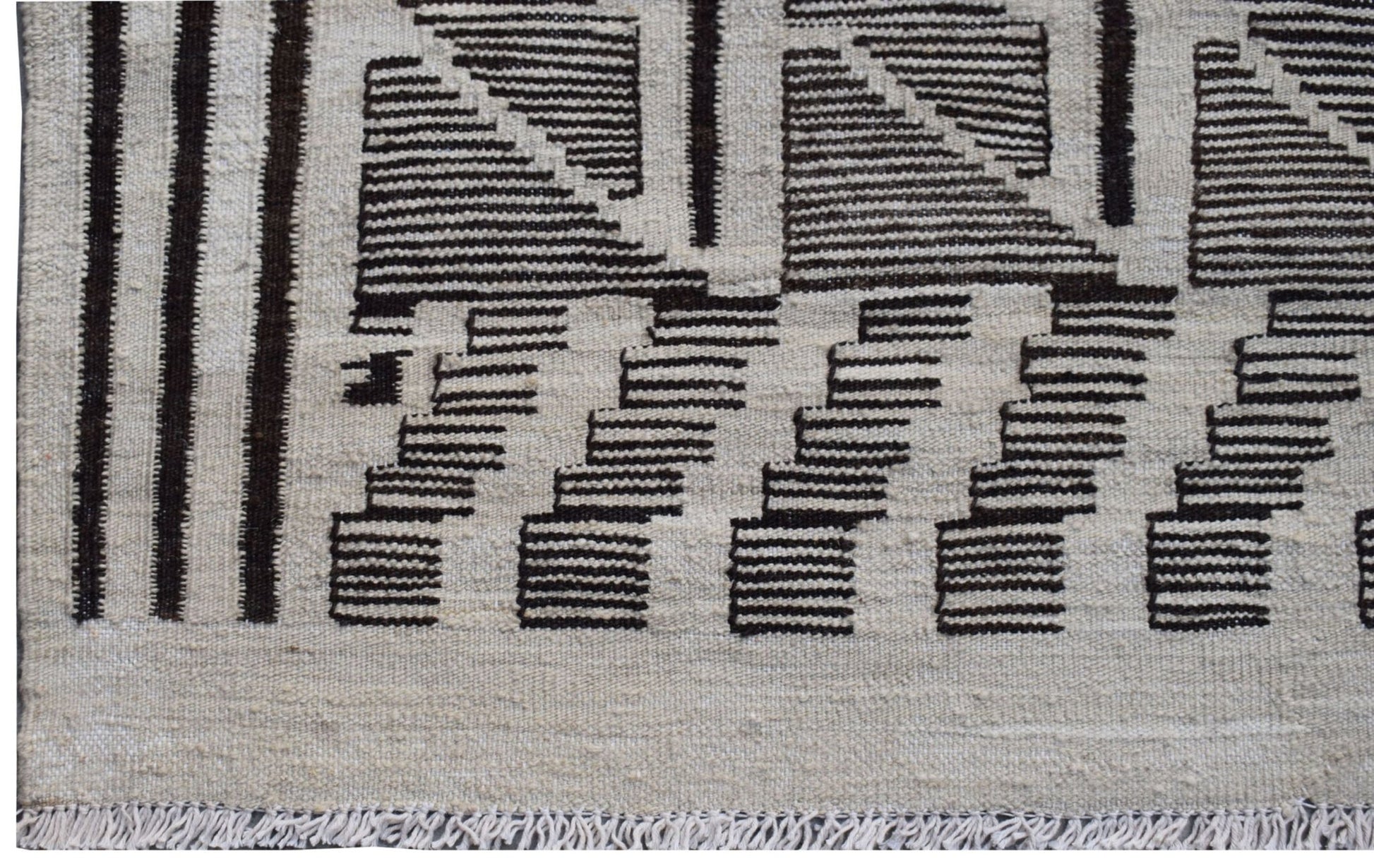 Handmade Afghan Maimana kilim rug featuring a geometric pattern in black and natural wool tones.