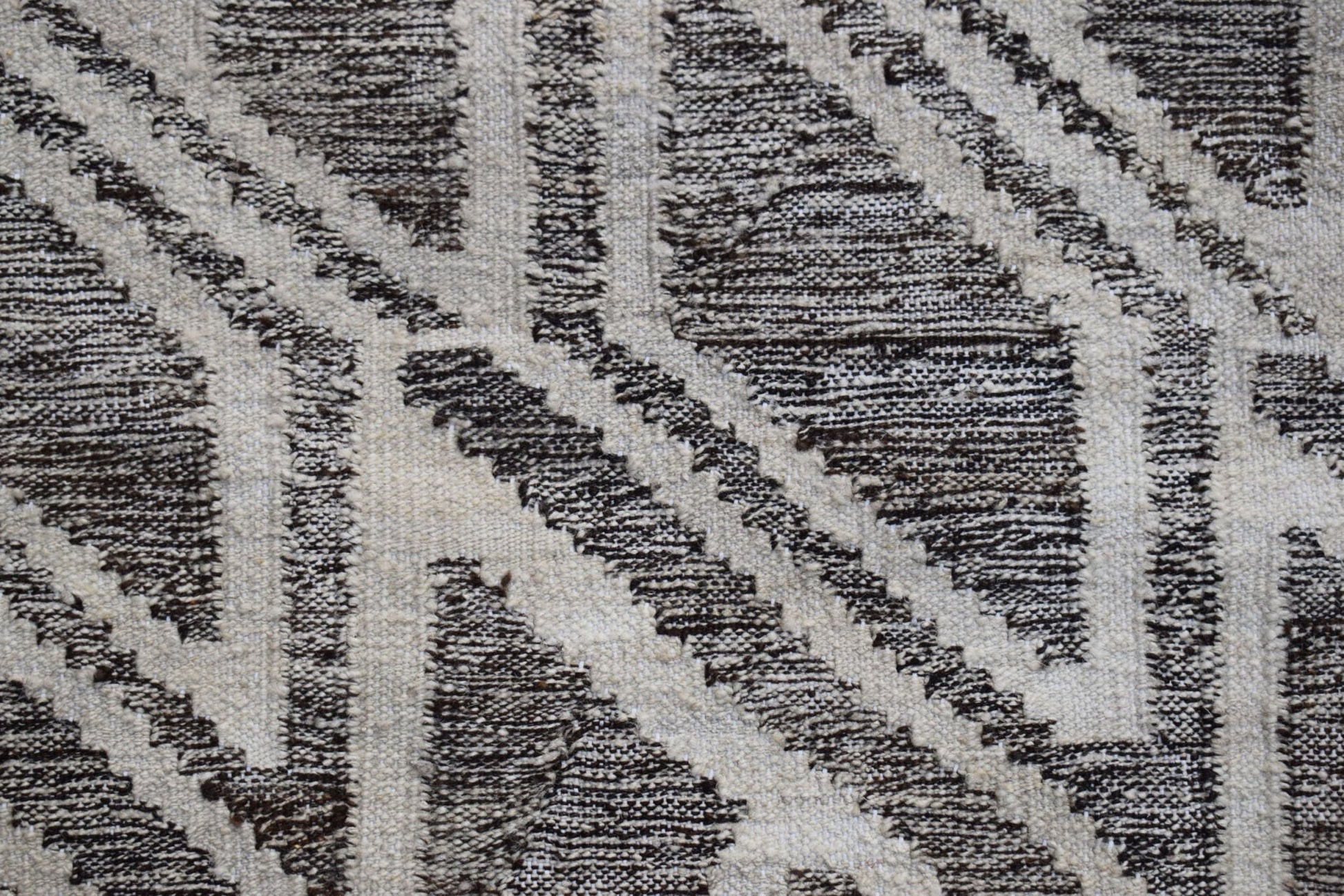 A handmade Afghan Maimana kilim rug featuring a geometric pattern in dark brown and cream wool.
