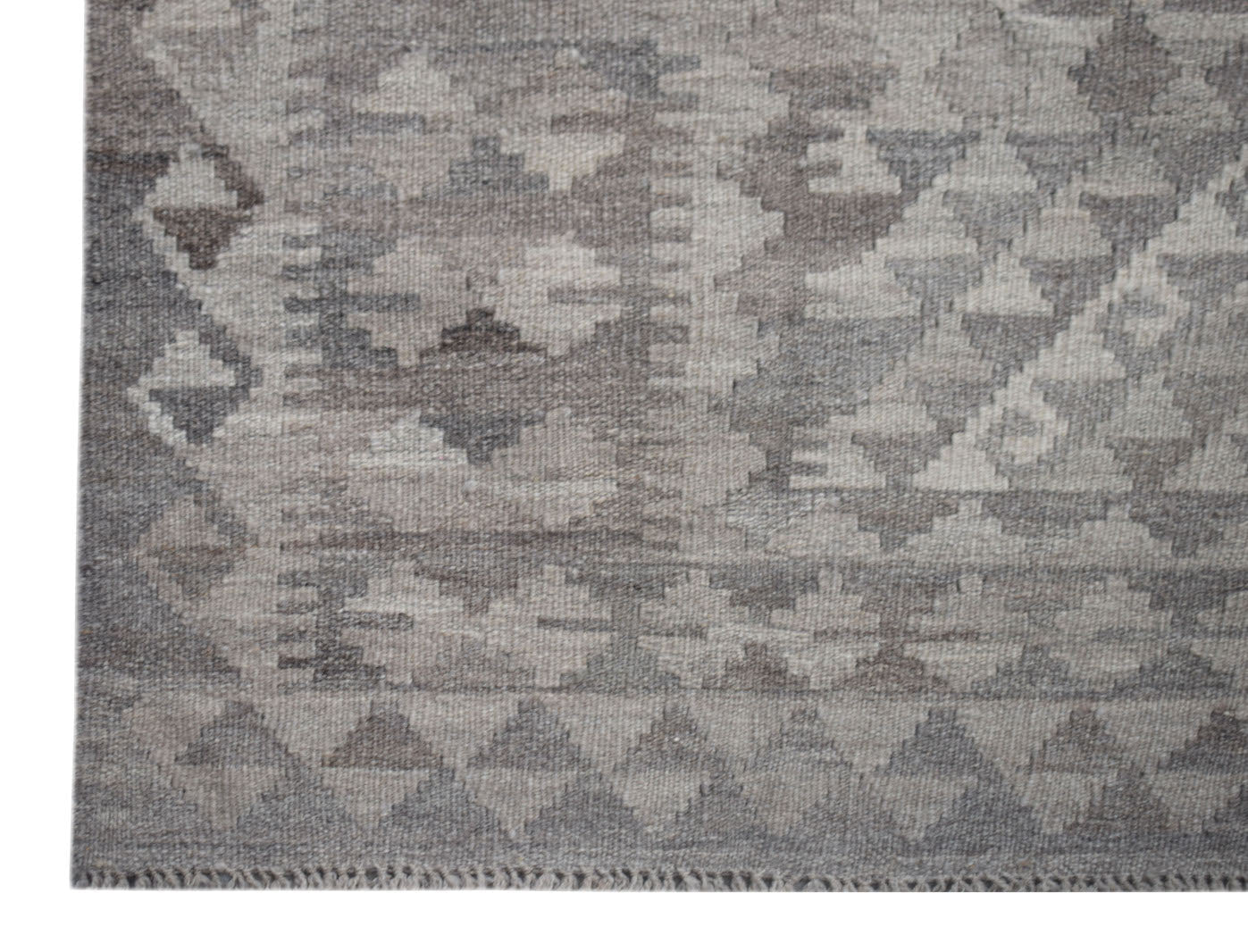 A handwoven Afghan Maiamana kilim rug featuring a grey geometric pattern in undyed natural wool.