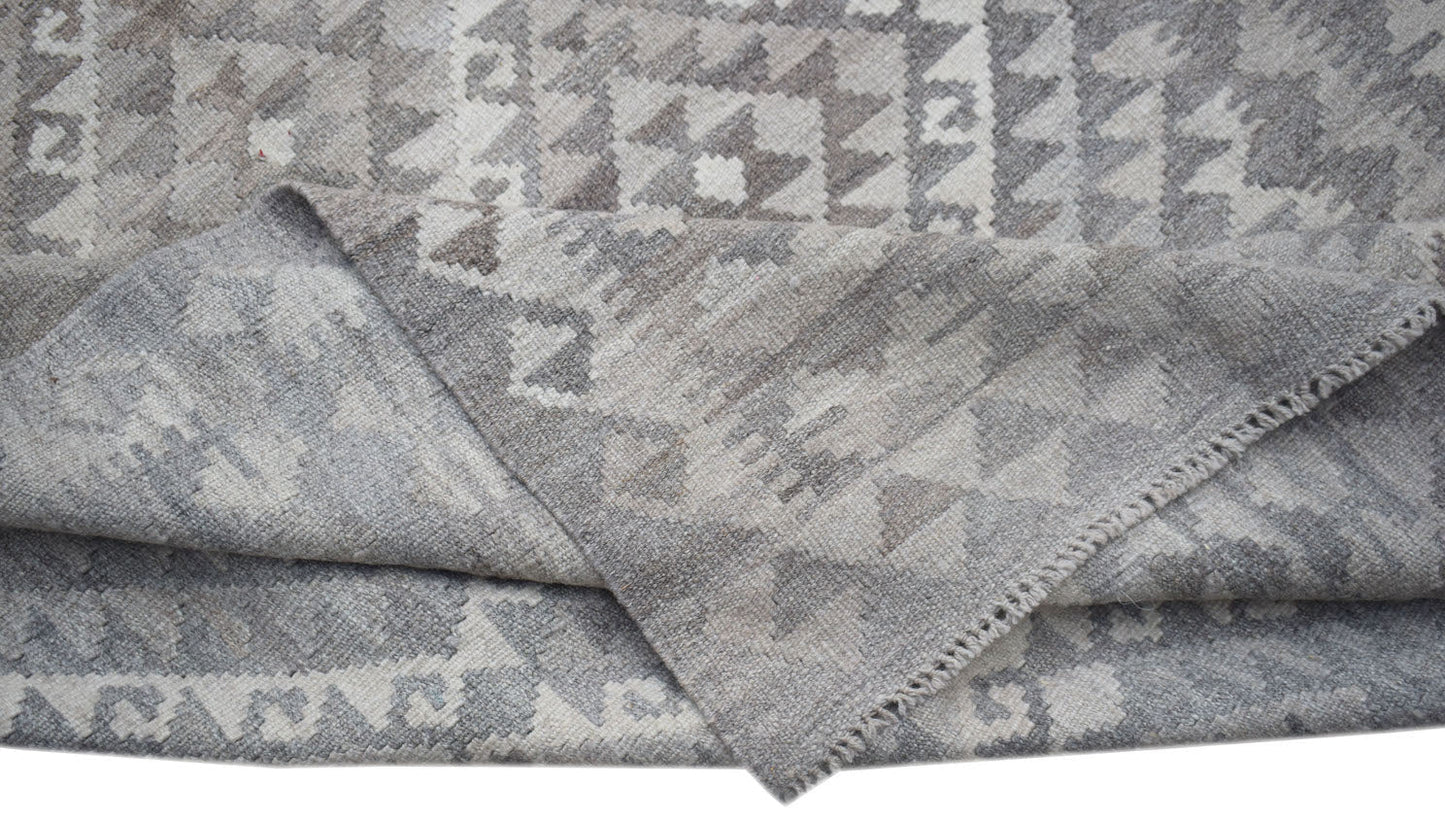 A handwoven Afghan Maimana kilim rug featuring a grey and white geometric pattern.