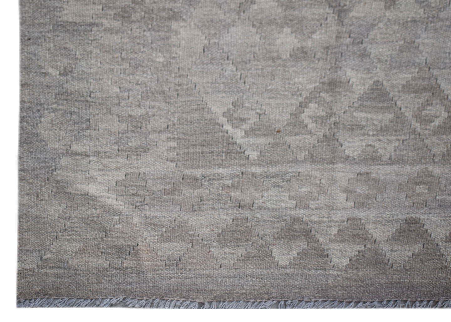 A handwoven Afghan Maimana kilim rug featuring a neutral geometric pattern in undyed wool.