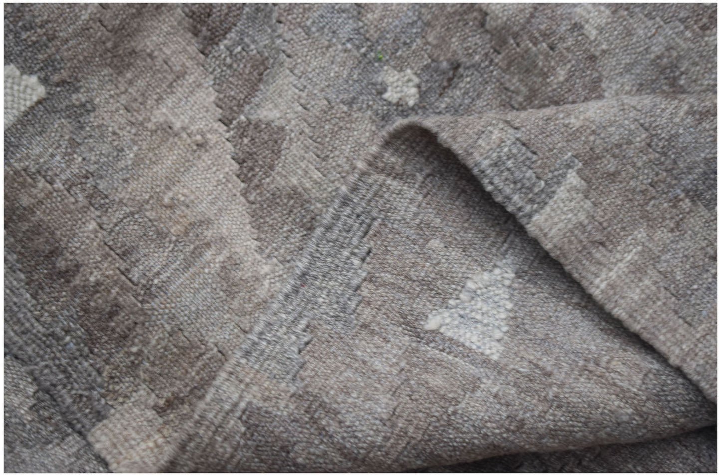 A handwoven Afghan Maimana kilim rug featuring a neutral geometric pattern in undyed wool.