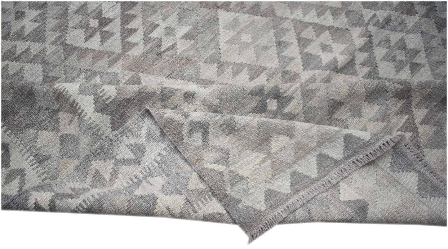 A handwoven Afghan Maimana kilim rug featuring a geometric pattern in shades of grey and white.