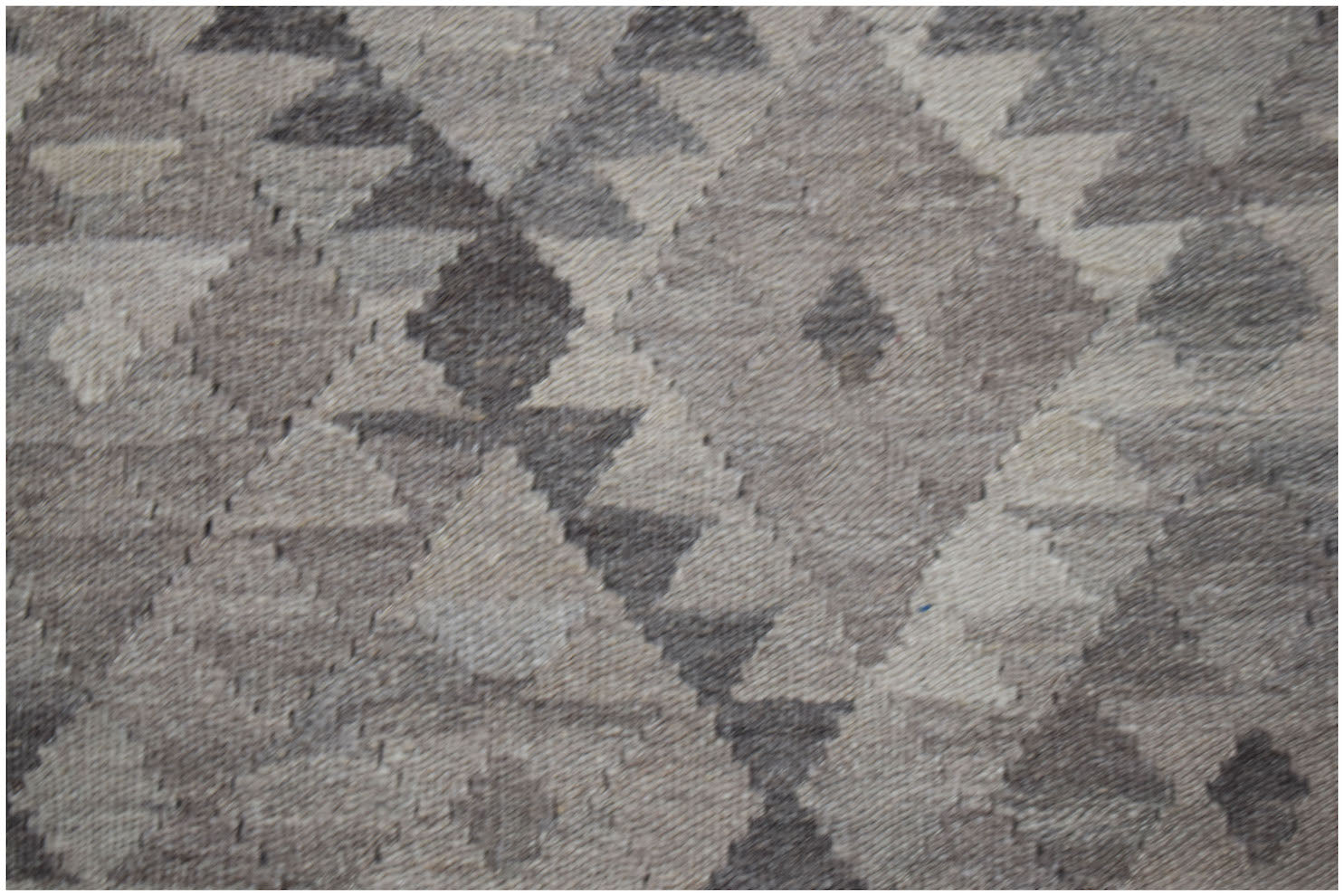 A handwoven Afghan Maimana kilim featuring a geometric diamond pattern in shades of grey and white.
