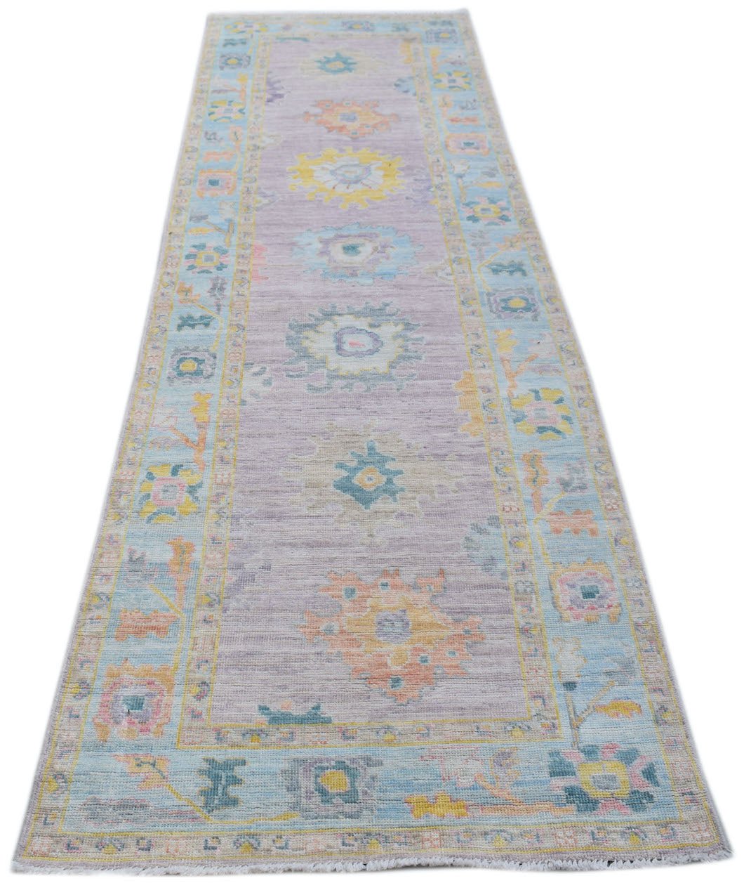 A handmade wool runner rug featuring a traditional Oushak pattern in soft pastel tones.