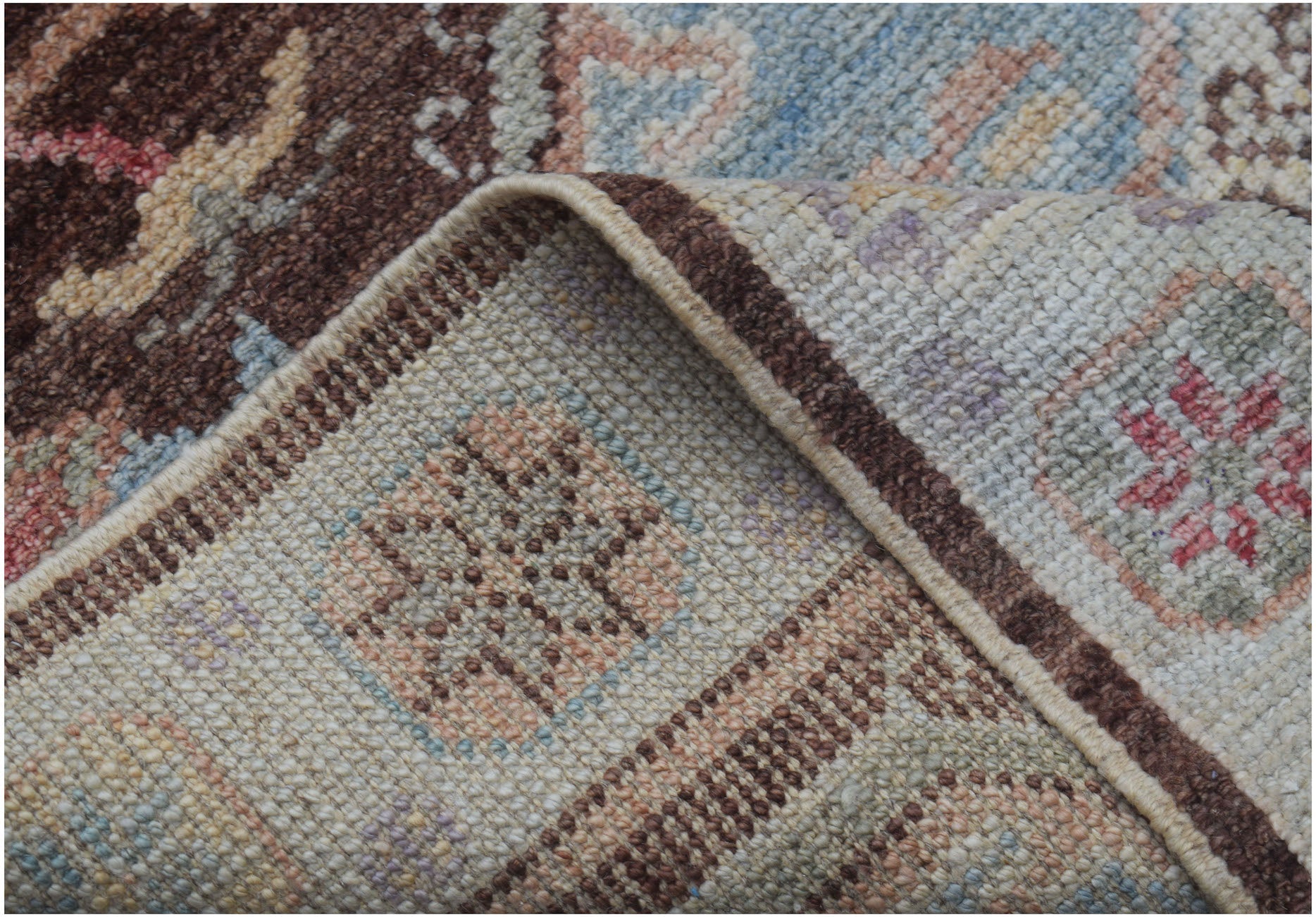 A close-up view of a handmade wool runner rug featuring a traditional pattern in brown and blue.