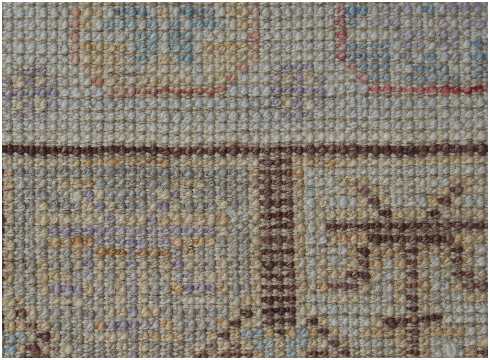 A close-up of a handmade wool runner rug featuring a traditional pattern in muted earth tones.